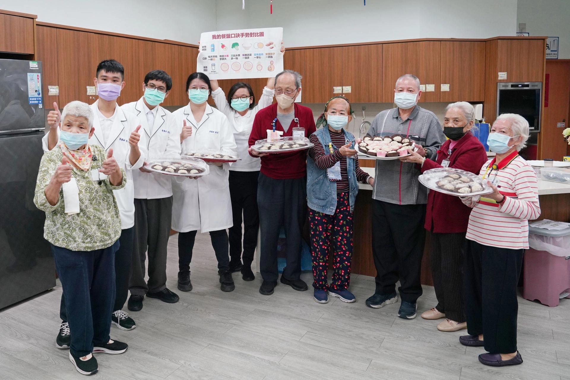 長輩們端著「燕麥棗泥元宵」成品，高興的與營養師一起慶祝營養師節快樂