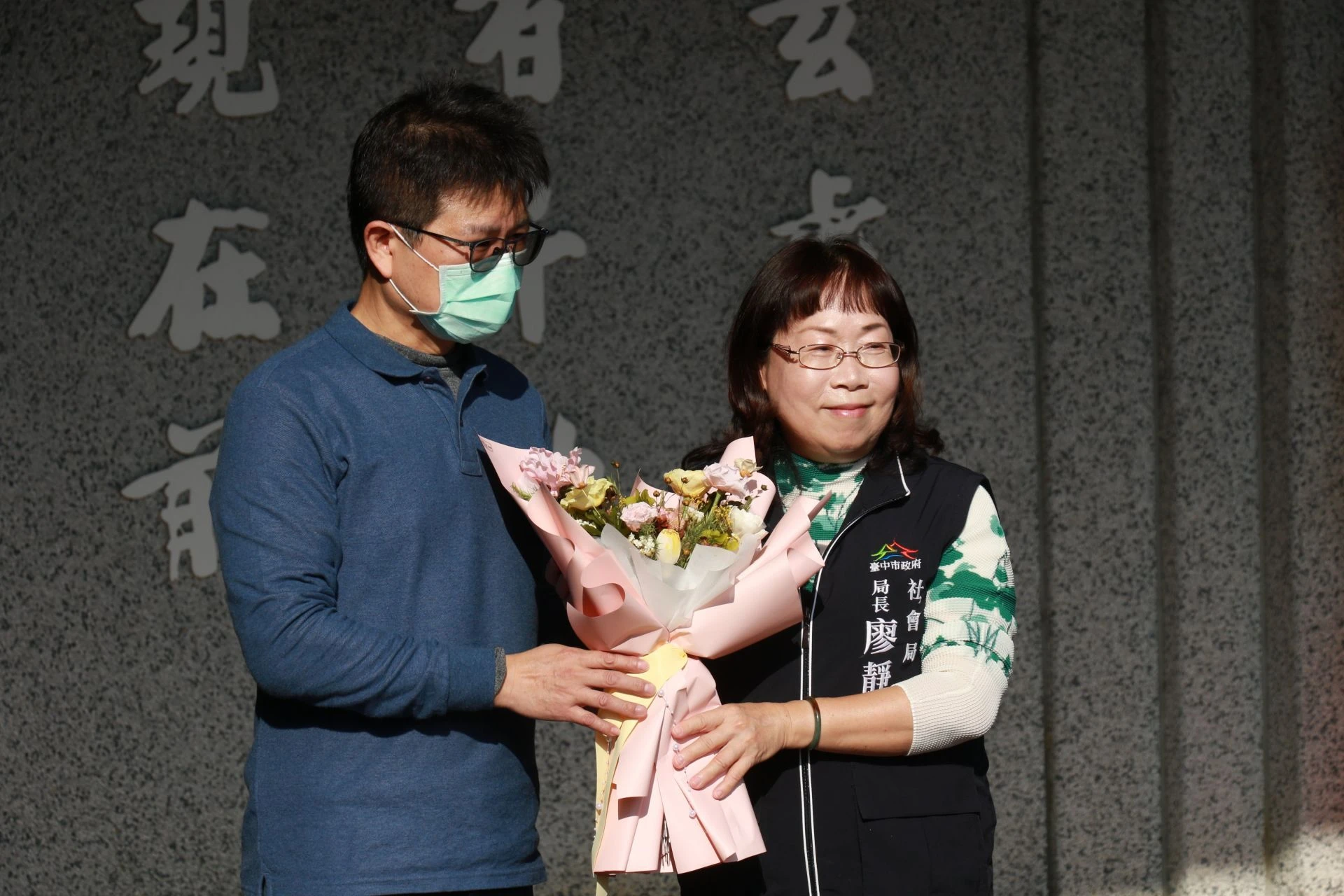 社政床家屬謝先生（左）代表獻花給臺中市政府社會局長廖靜芝（右）表達感恩。