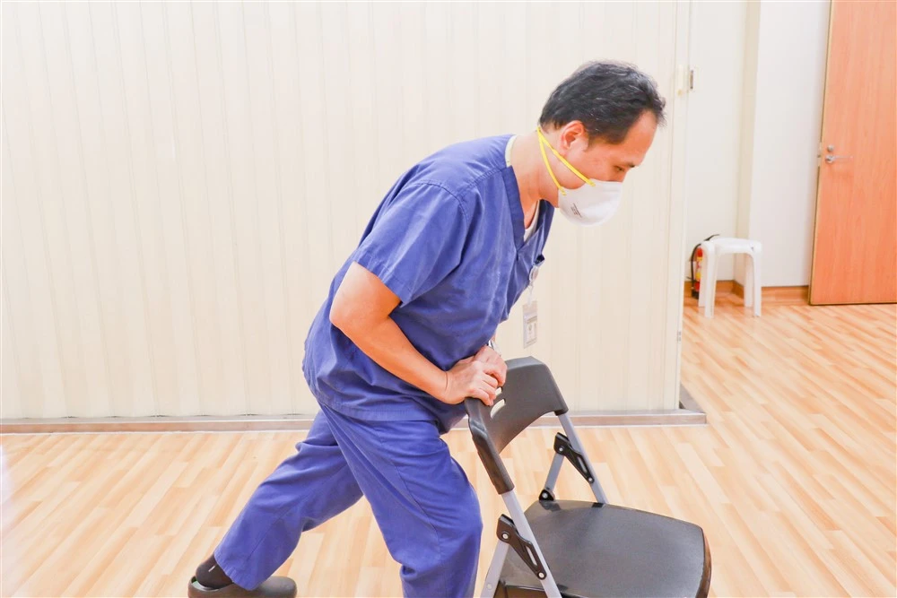 莊浩凌醫師示範自己一人的哈姆立克法，找到穩固桌椅，頂住肚臍與劍突的中間處用力推擠。