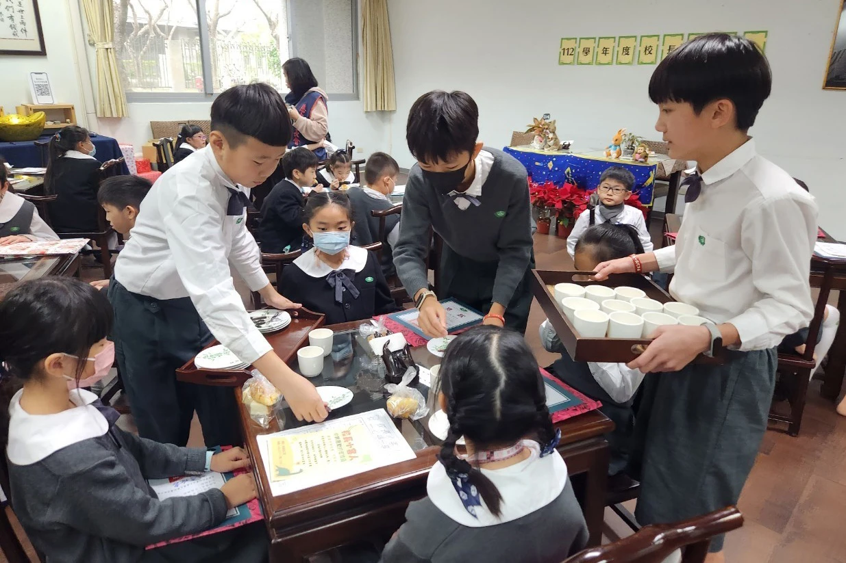 茶會結束前，六年級的大哥哥們，主動幫弟弟妹妹們收拾桌上的茶具與點心盤。