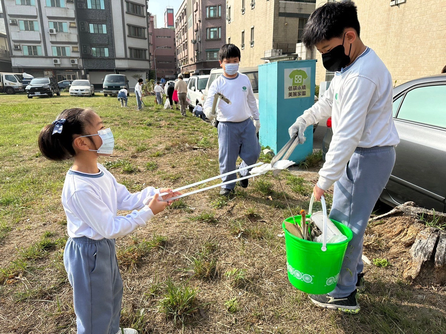 小朋友仔細地撿起草叢中的垃圾。