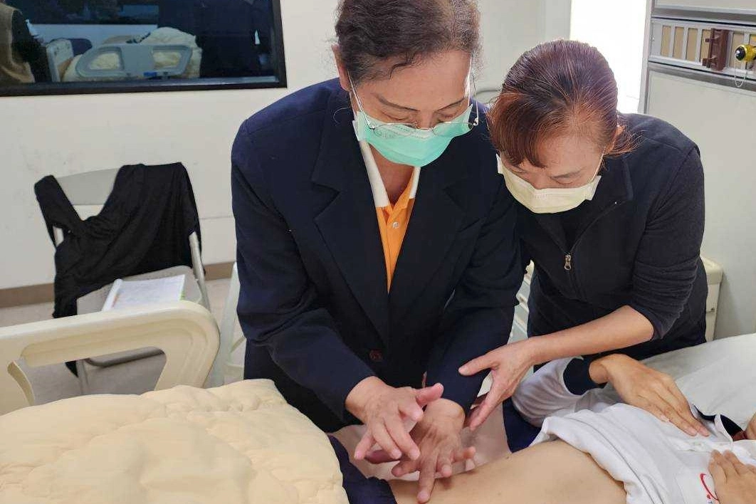 謝美玲老師以「手把手」教學方試，與彭台珠主任一起執行身體評估。