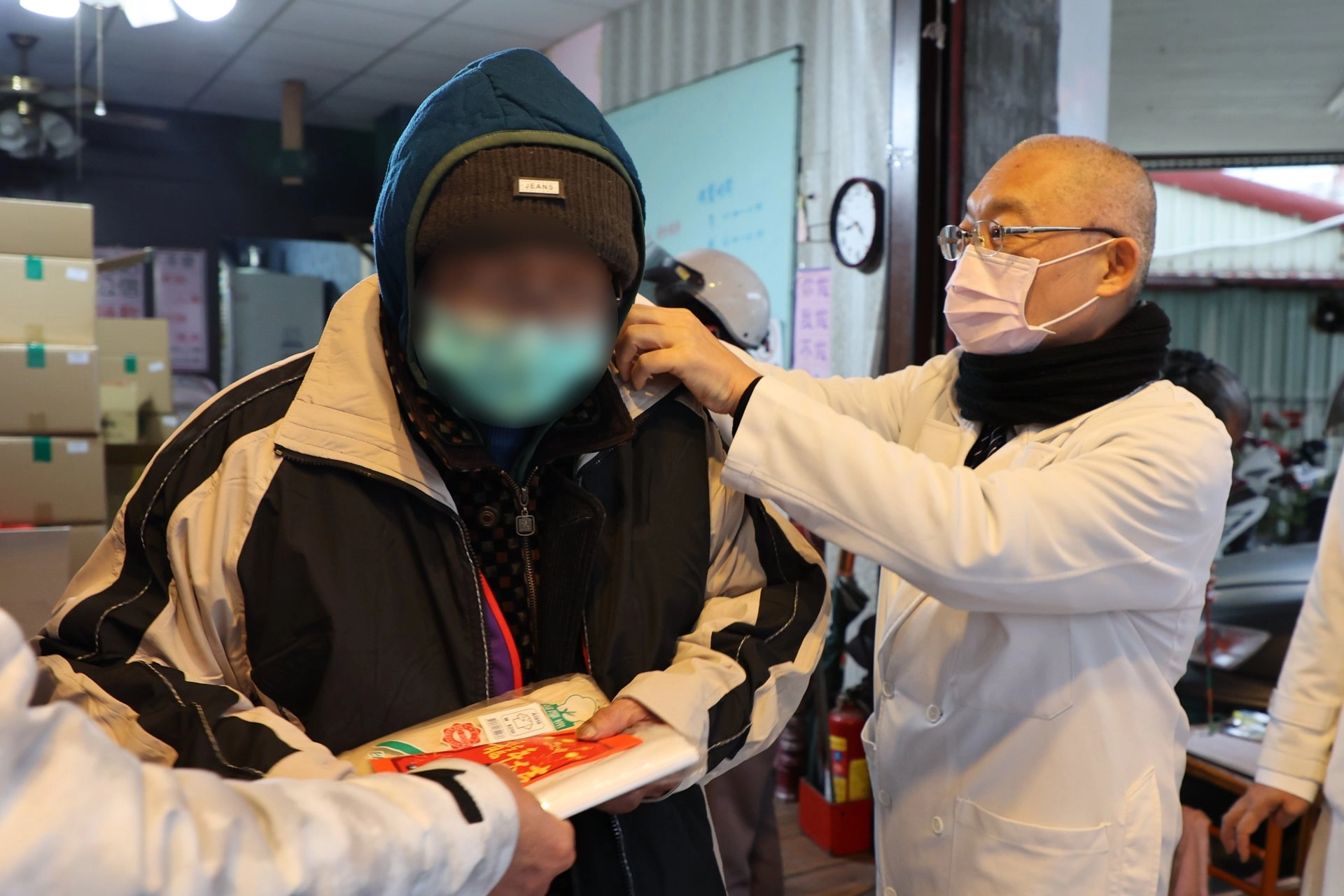 牙科部特殊需求者口腔醫學科主任李彝邦(右)，送上禦寒的外套，讓暫駐在人安基金會的李先生(左)很溫暖也很感動。