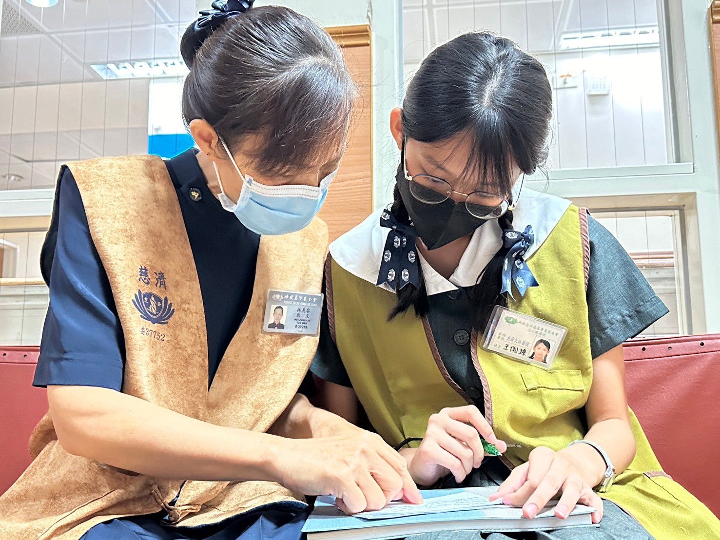高中王俐臻同學(圖右)跟著師姑學習寫下訪視病人的重點。