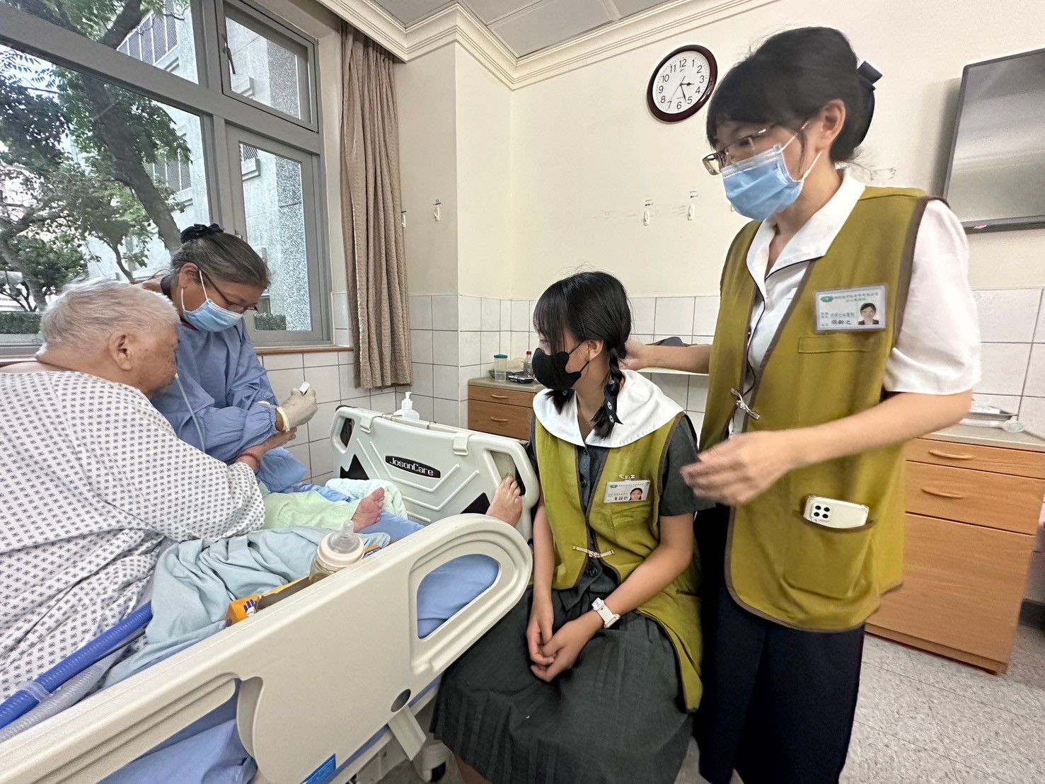 張齡之主任(圖右2)與高中黃穎歆同學(圖中)共同關心病房的老人家。
