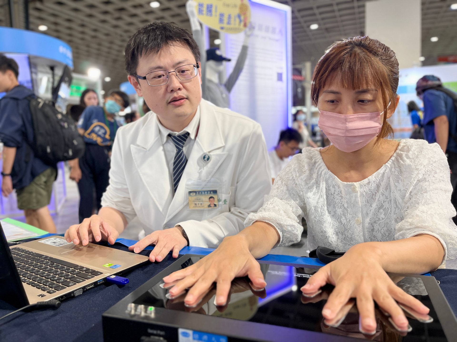 陳中奎醫師(左)操作能量檢測儀，為民眾解說。
