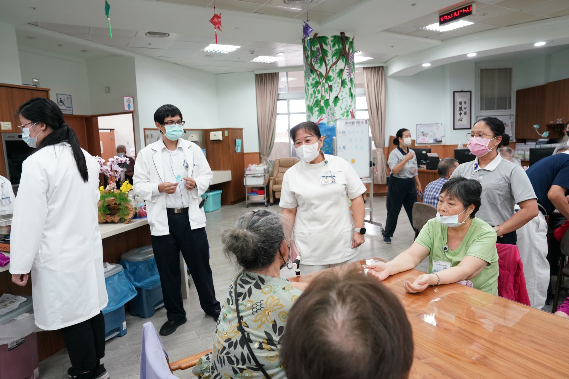 同心圓日照中心主任張幸齡(中)介紹梁榮顯營養師(左二)給長輩們認識。