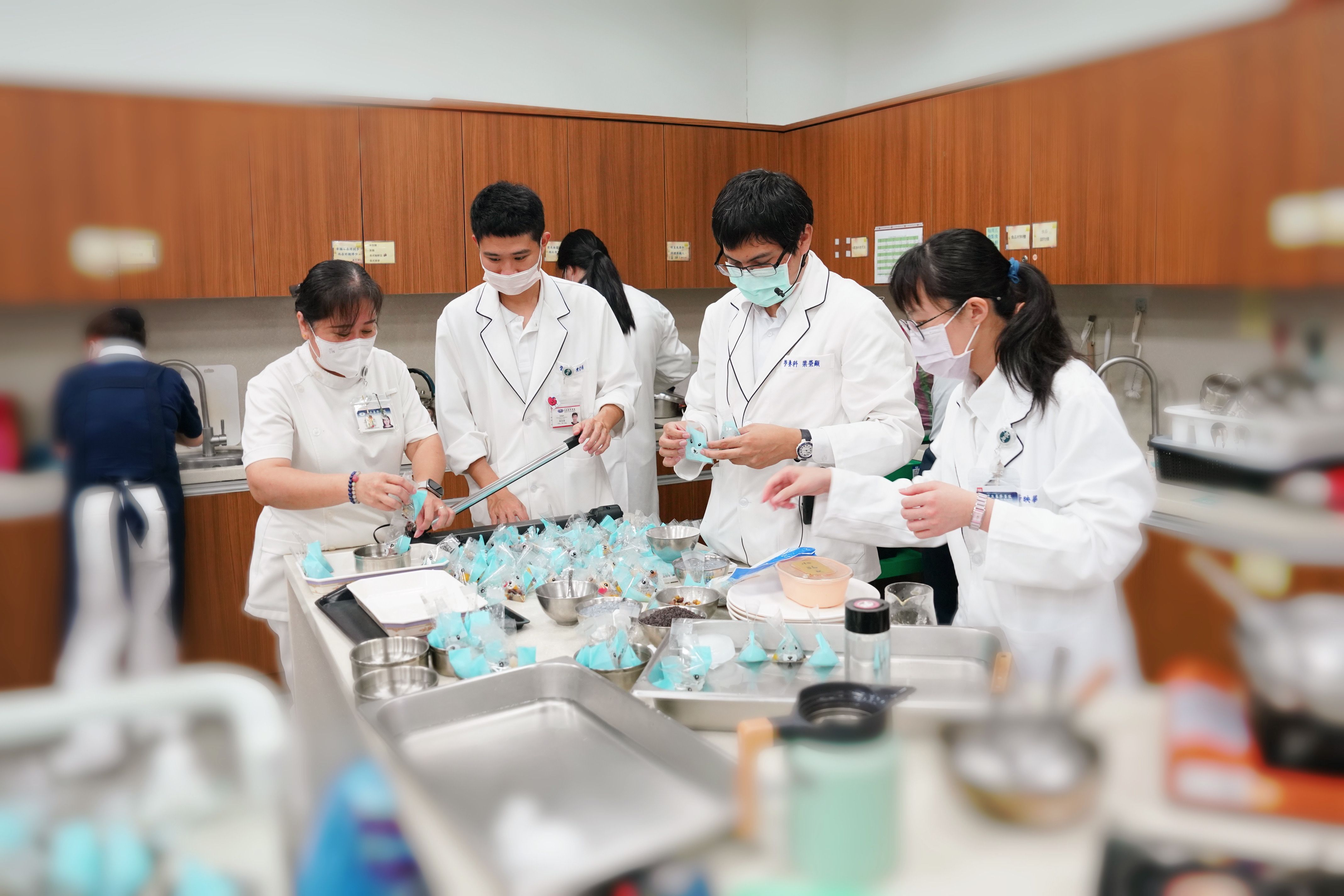 張幸齡主任(左二起)、陳哲揚、梁榮顯、林佩萱、三位營養師聯合為同心圓日照中心長輩封裝水果八寶粽。