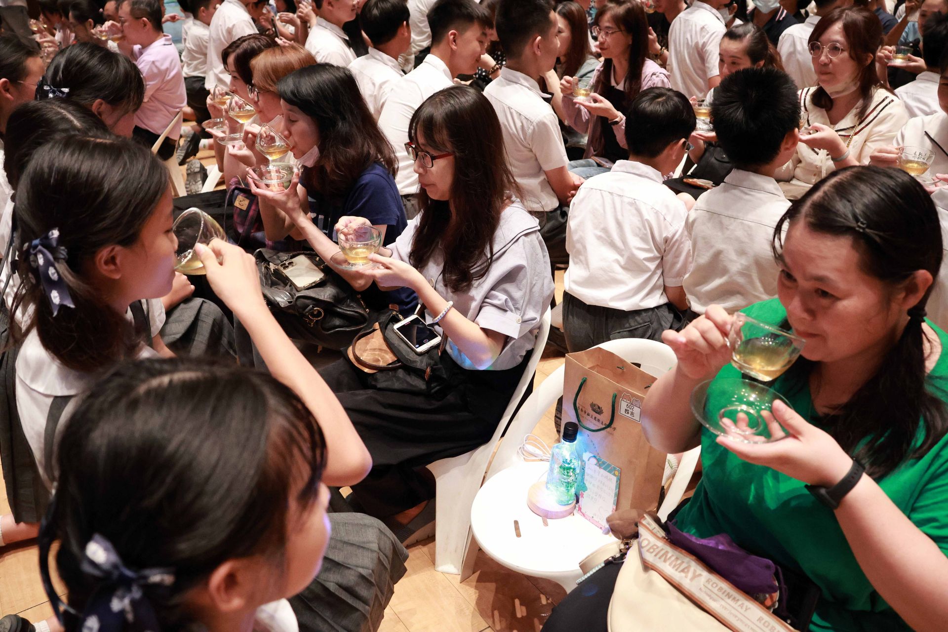 畢業生恭敬的以一杯茶水與手製浮游花影燈禮敬父母，感恩父母的養育之恩與無私付出。
