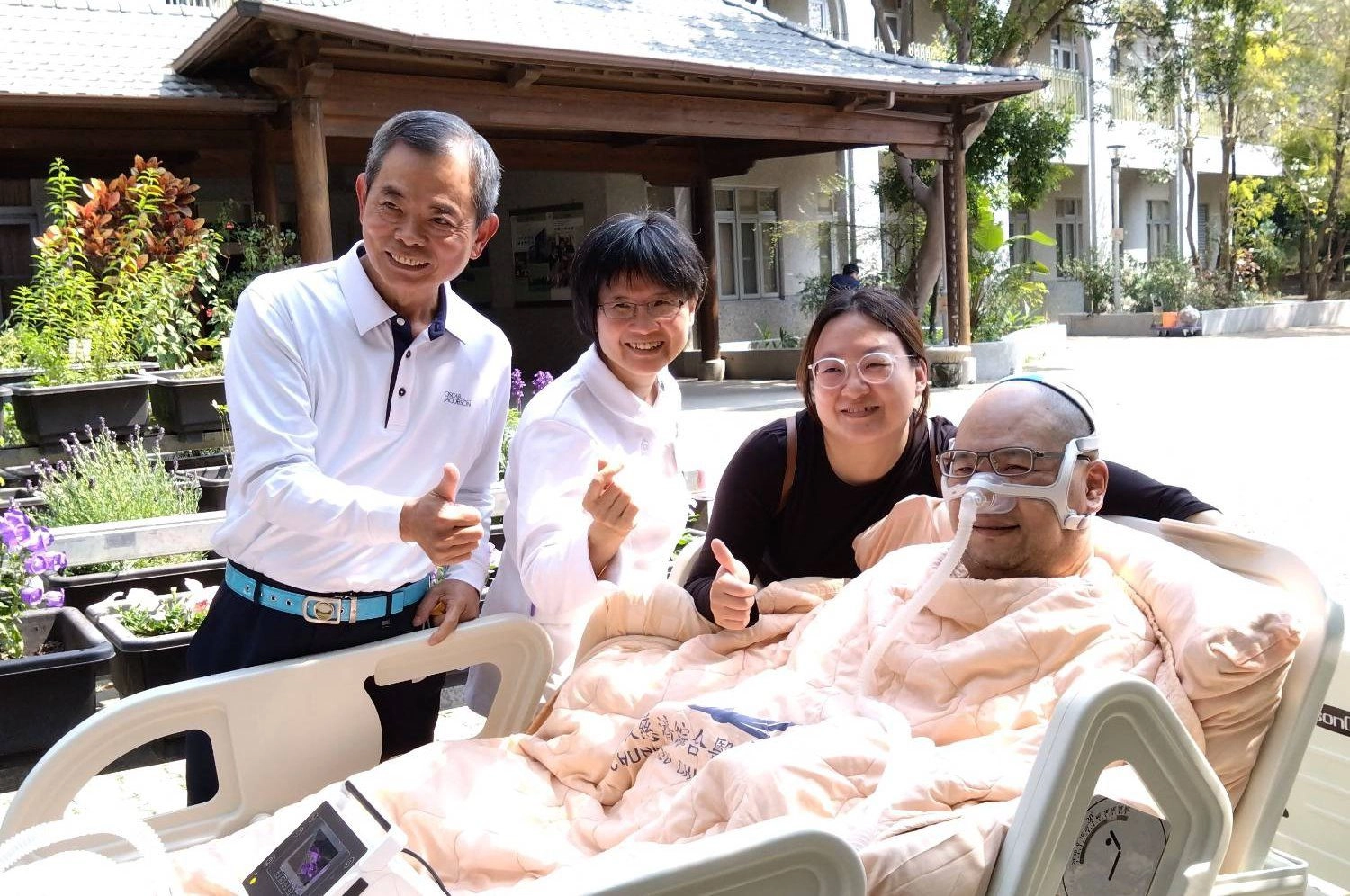 台中慈濟醫院心蓮病房護理長黃美玲（左二）、醫療志工（左一）陪伴黃鼎承（右一）與黃太太（右二）到病房外吸收陽光的滋潤。
