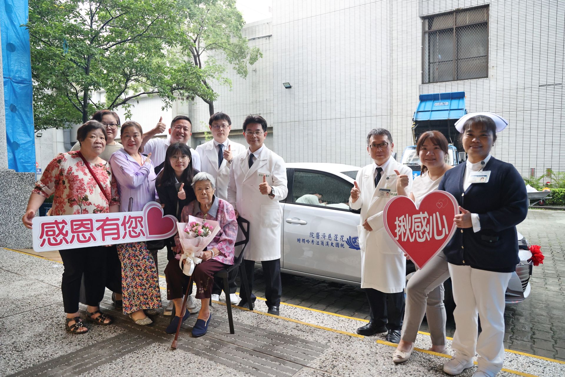 花蓮慈濟醫院何宗融副院長(左八)帶領中醫部代表，與大愛捐車簡江秀吟女士(坐者)一家人，在新車前合照。