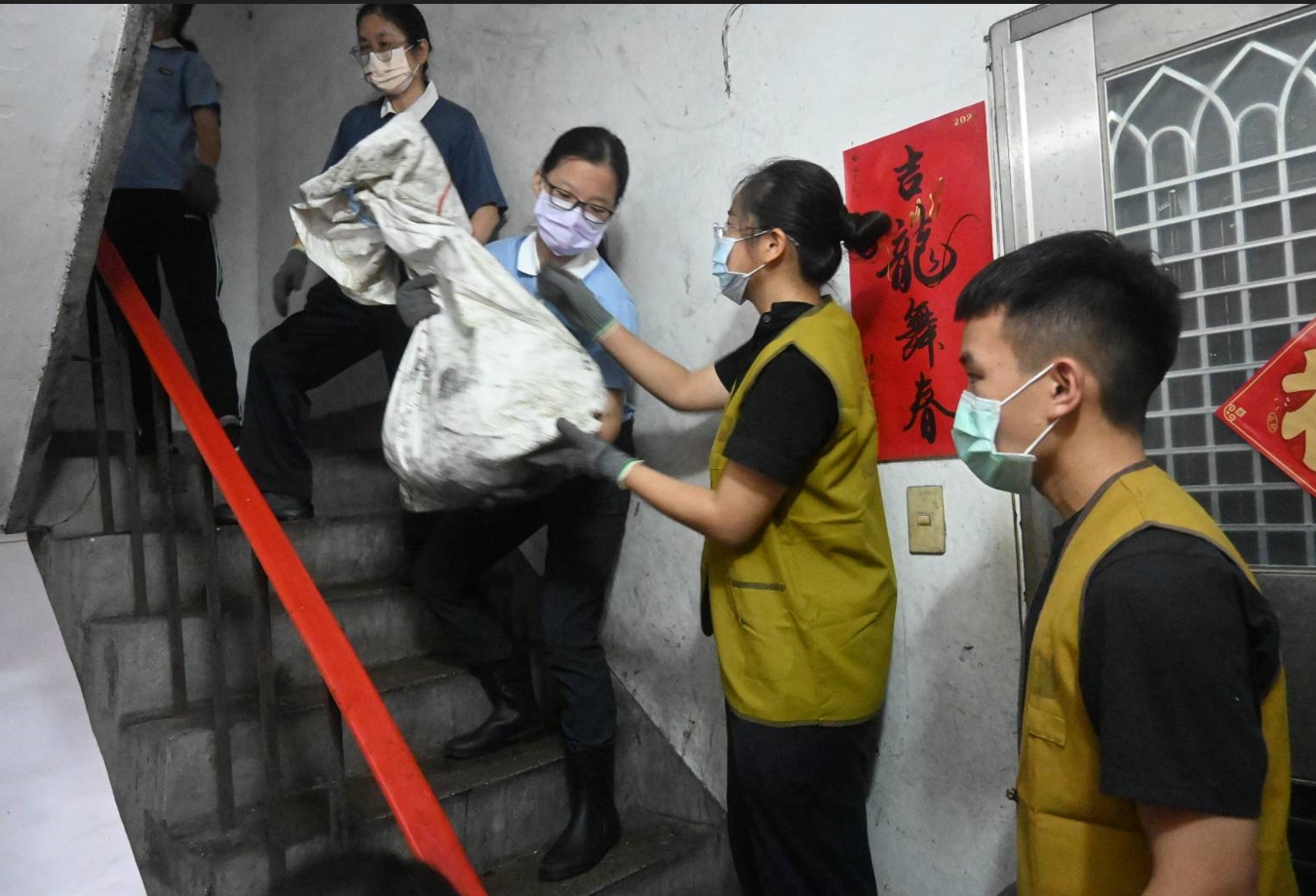 年輕人接力將垃圾一袋一袋傳下來。