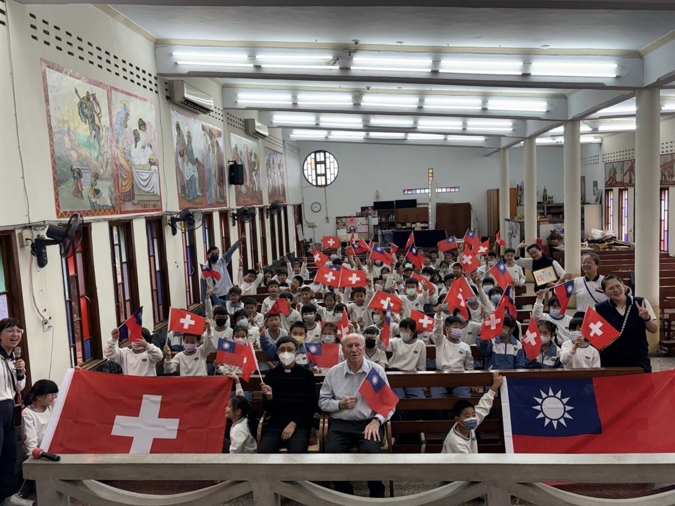傅若望神父與孩子們舉著中華民國與瑞士國旗，象徵愛無國界