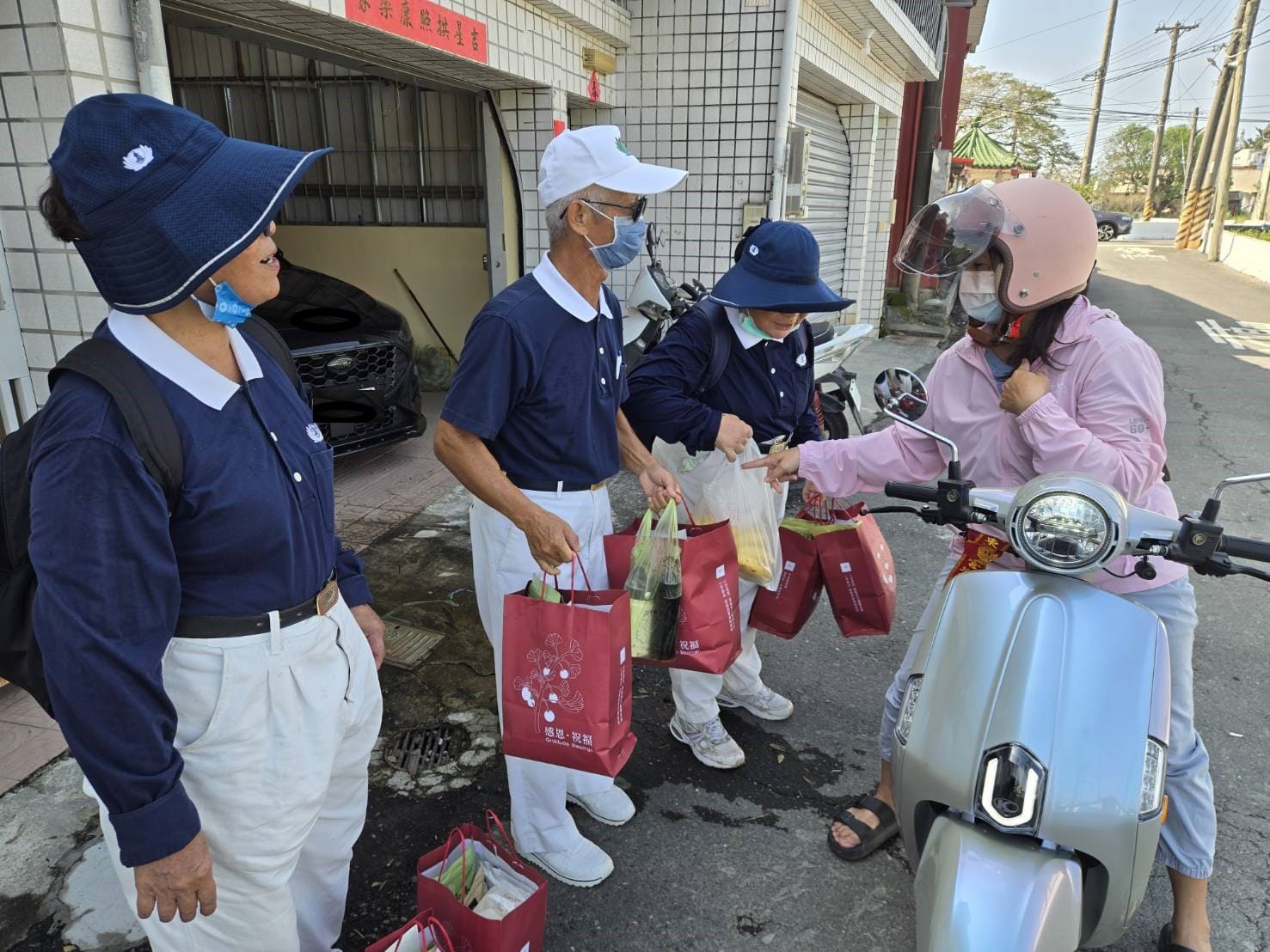女機車騎士騎機車路過看到路邊提著安心祝福禮的慈濟人，立即送上一袋香蕉要給慈濟志工享用，感恩慈濟人前幾天來發熱食便當