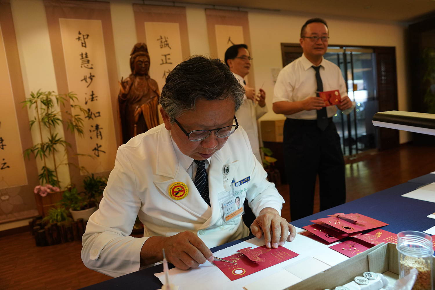 徐中平副院長，認真為福慧紅包沾黏象徵戒、定、慧稻穀。