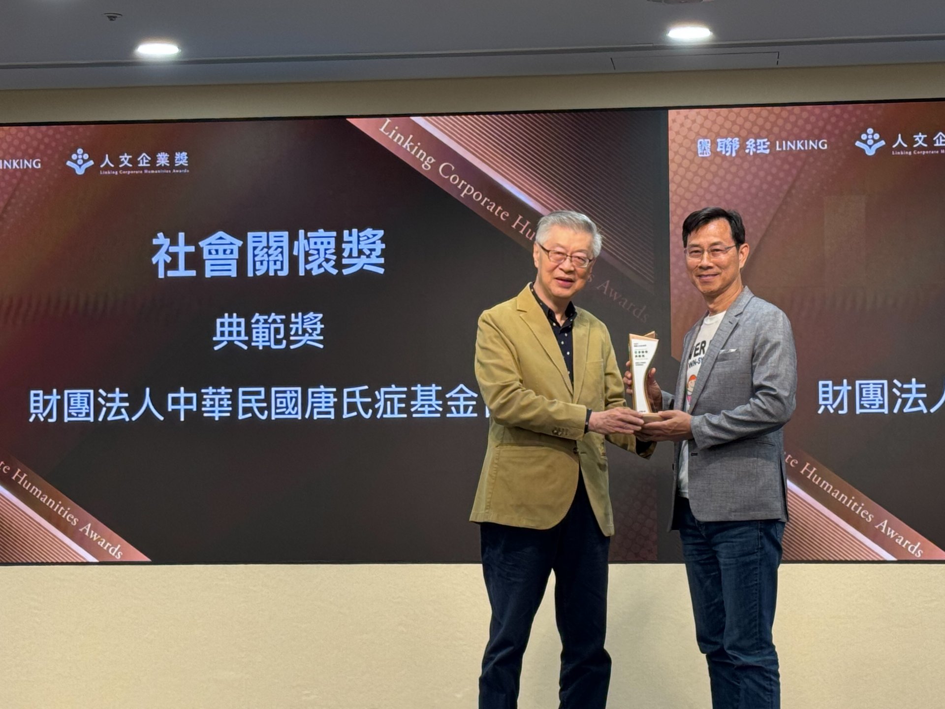 唐氏症基金會董事長林正俠（右）接受願景工程基金會董事長陳冲（左）頒發典範獎。