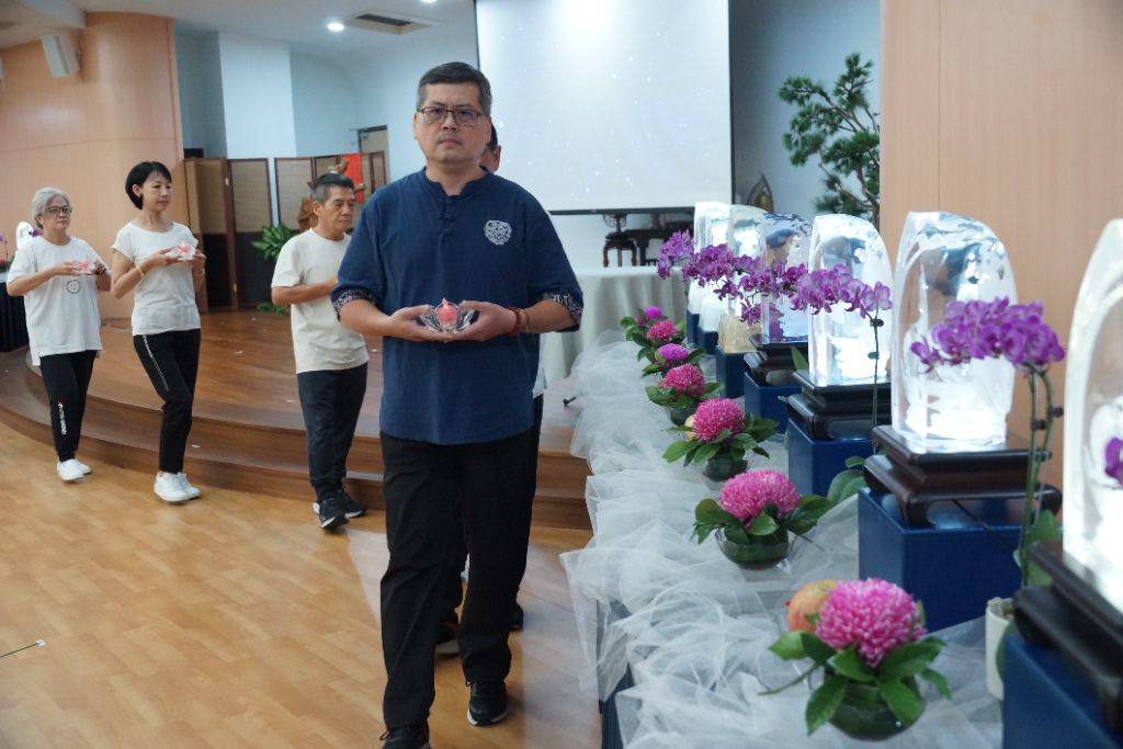 陶笛老師余培全(前)今日承擔獻供，他分享多年來與慈濟的因緣，常帶領學員至日照與長照中心義演，深刻體會上人所言「見苦知福」。