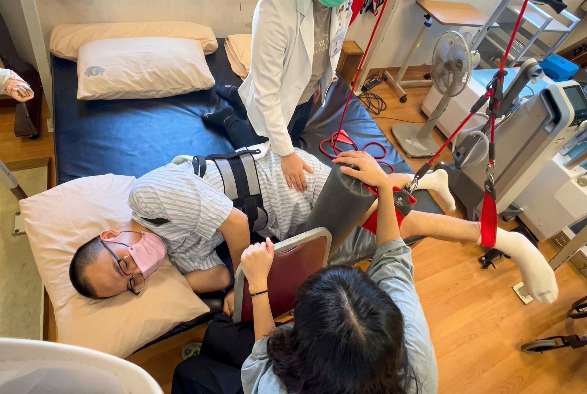 剛受傷不久的洺哲,下半身軟弱無力,只能靠機器吊起雙腳協助復健。