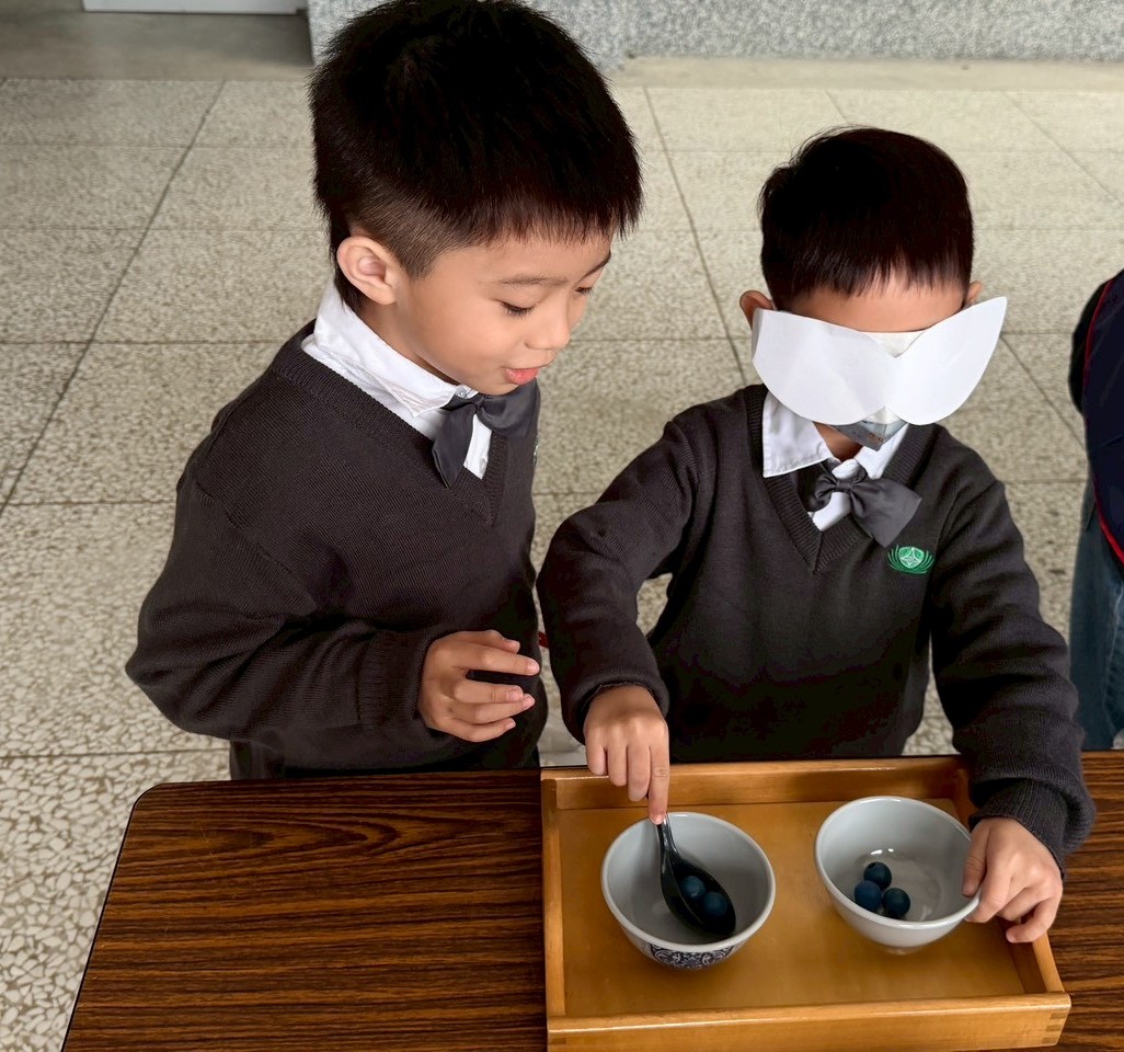 一年級海底撈月：明眼的小朋友認真的引導看不見的孩子，將珠子撈到另一碗中。