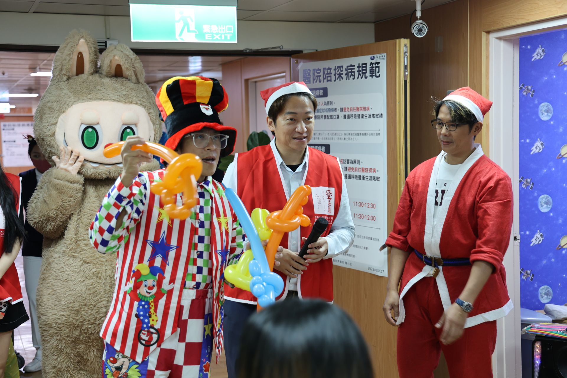 耶誕音樂一響起，雷恩叔叔（左一）大展魔術身手，氣球一下從「一變二」，逗得小朋友們驚呼連連。他還根據小朋友們的喜好將氣球折成寶劍、小狗與玩具槍等造型。