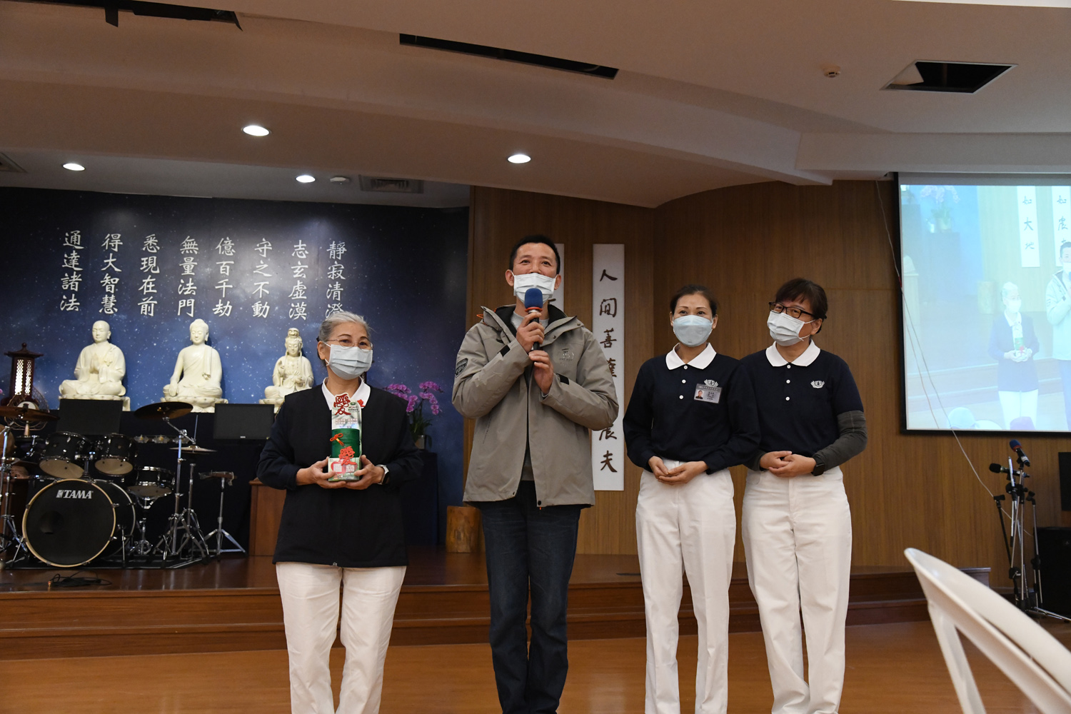 在志工吳玲華(左一)邀請下,「大莊香酥臭豆腐」的黃崧烈(左二)首次走入新竹靜思堂參加歲末祝福,與會眾分享他與慈濟的因緣。