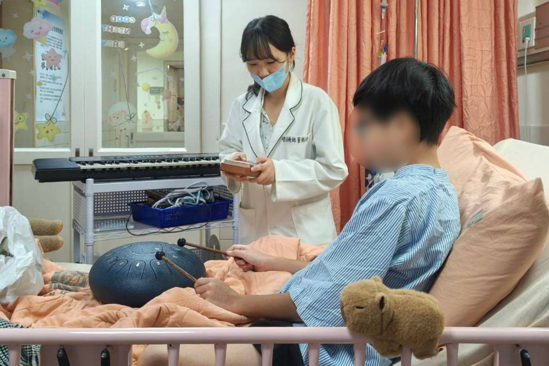 藝術治療師與音樂治療師到病房，藉由音樂與手作遊戲，減輕樂樂住院不安的情緒。