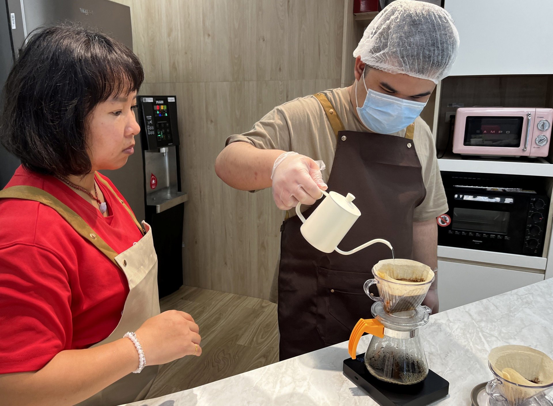 小育(右)在伊甸教保員莊嫚婷(左)的指導與陪伴下，逐漸熟悉手沖咖啡的技巧。