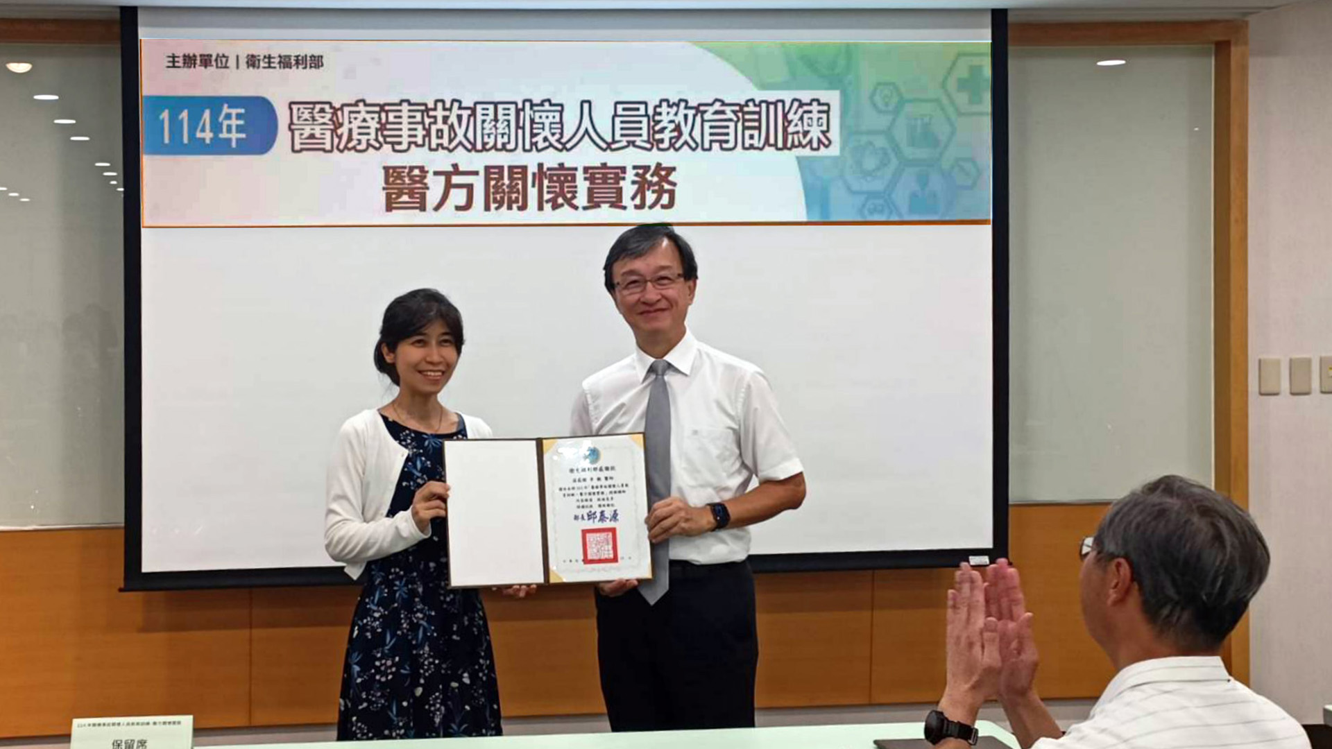 承辦單位財團法人藥害救濟基金會執行長陳文雯(左)頒發衛福部感謝狀給李毅醫師。
