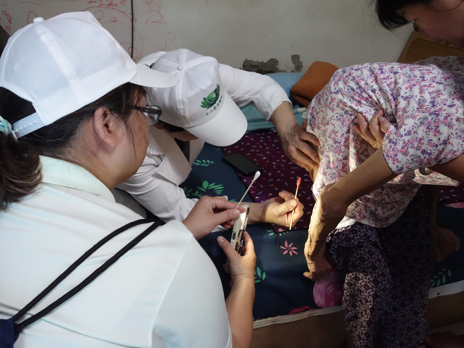 簡瑞騰副院長關懷受災戶時，協助一位90歲阿嬤褥瘡清創。