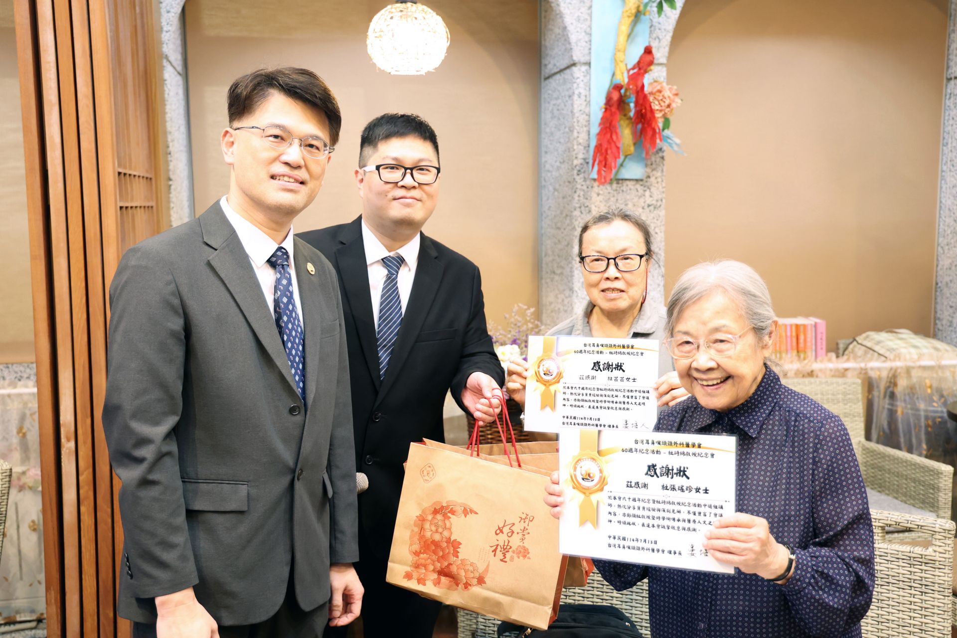台灣耳鼻喉頭頸外科醫學會副祕書長廖立人(左)頒發感謝狀予杜詩綿院長的夫人張瑤珍女士(右一)及女兒杜芸芸(右二)，表達對杜院長的感恩與思念。