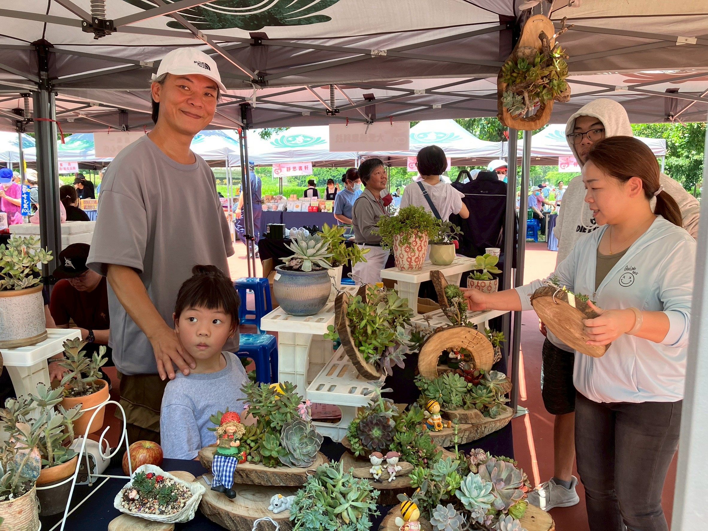 志工劉碧蓮承擔的多肉植物攤位，由兒子羅秉文和孫女幫忙義賣。