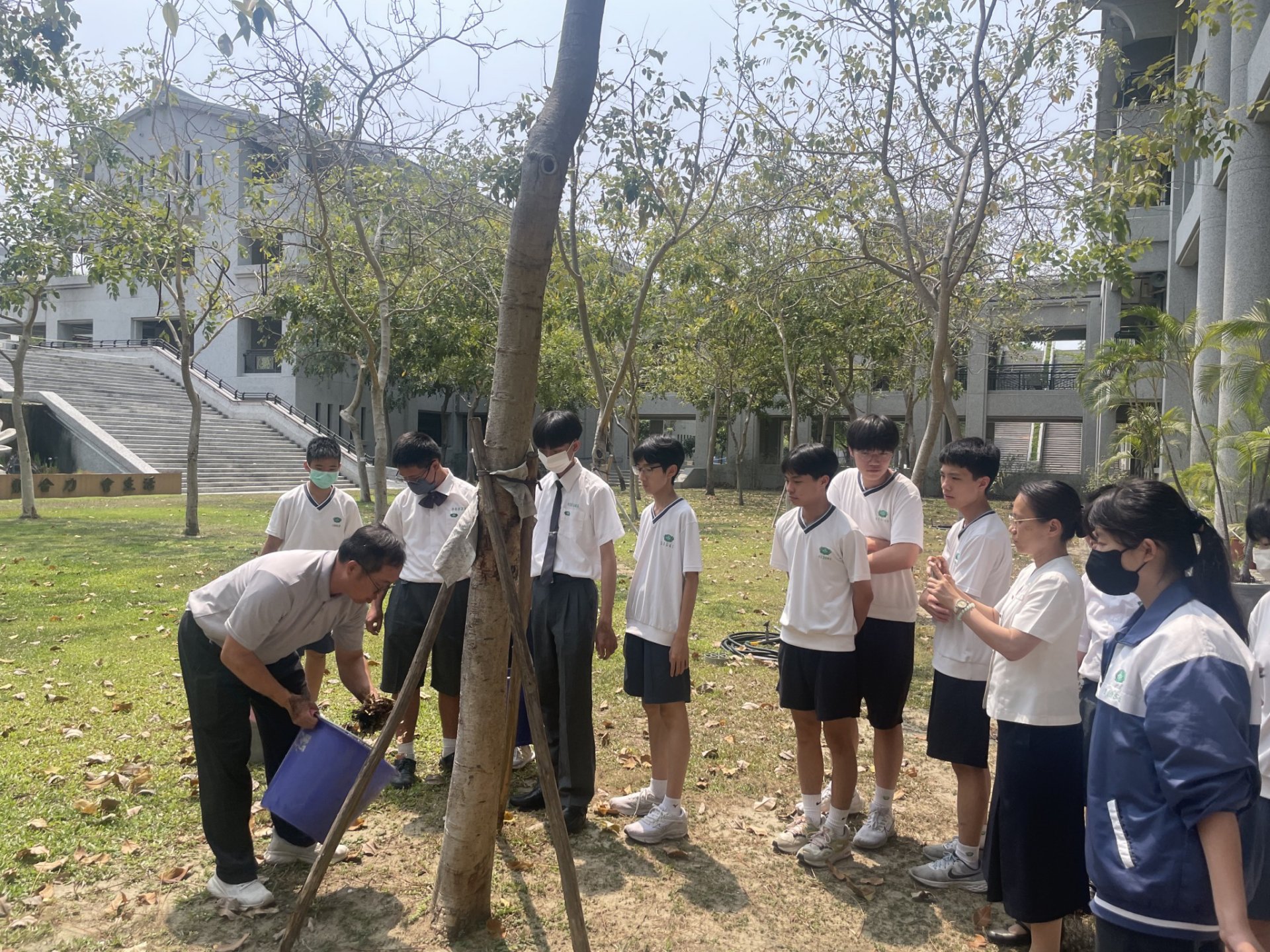 總務處同仁向校內師生示範落葉堆肥使用方式，推動環境永續。