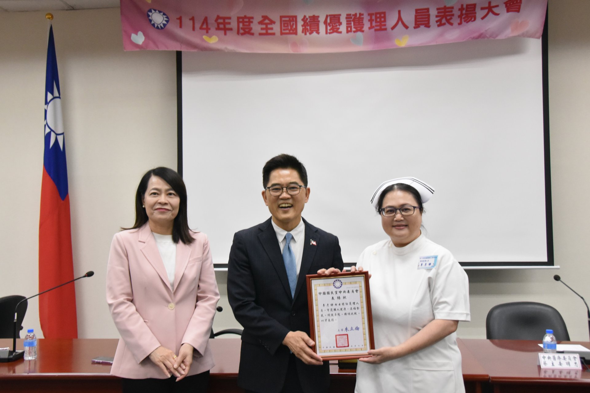 經護理師公會全聯會推薦，花蓮慈濟醫院護理部督導李彥錚(右)獲國民黨全國績優護理人員表揚。頒獎人為國民黨秘書長黃健庭(中)。