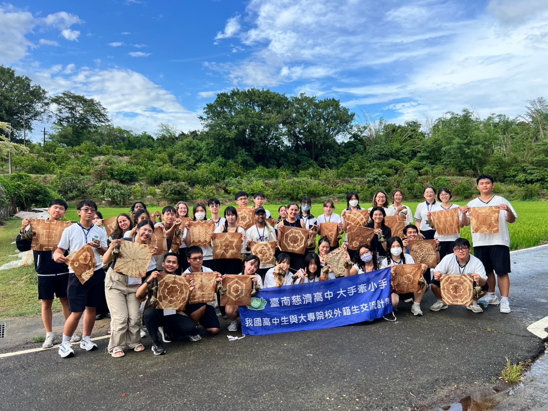 雨後放晴，臺南慈中師生與成大外籍生帶著親手染製的作品拍照留念。