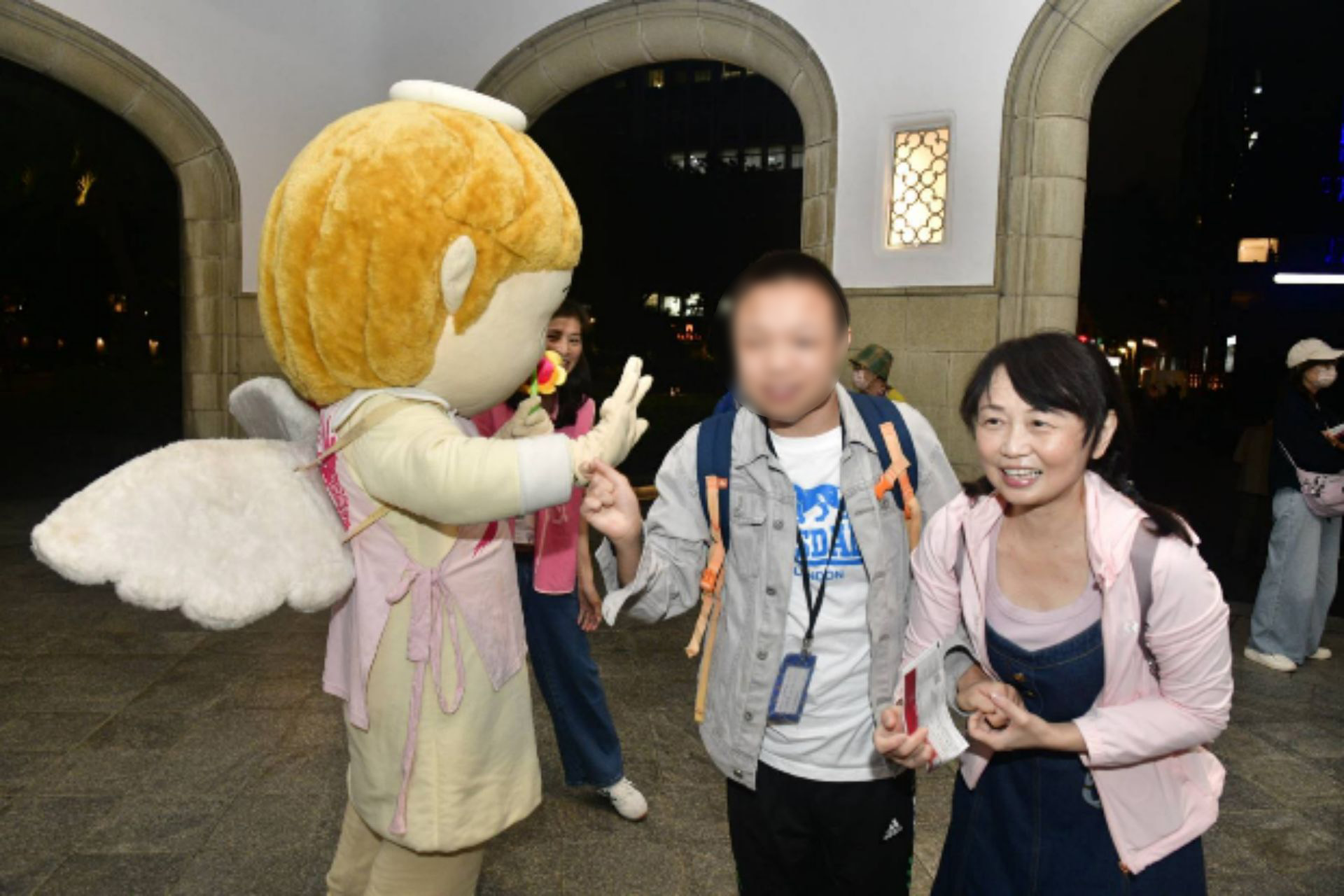 晶晶天使於臺北市中山堂門口迎接愛奇兒家庭進場聆聽音樂會。