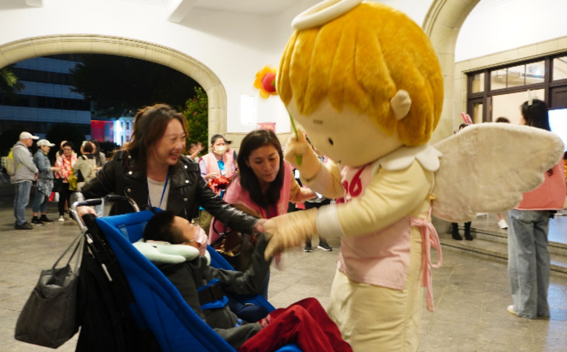 晶晶天使於臺北市中山堂門口迎接愛奇兒家庭進場聆聽音樂會。