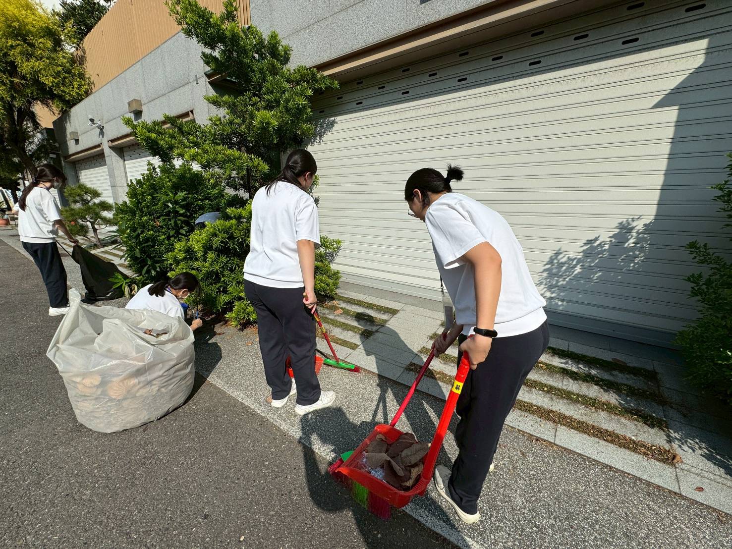 學生走入鄰里，協助清掃住家門前落葉。