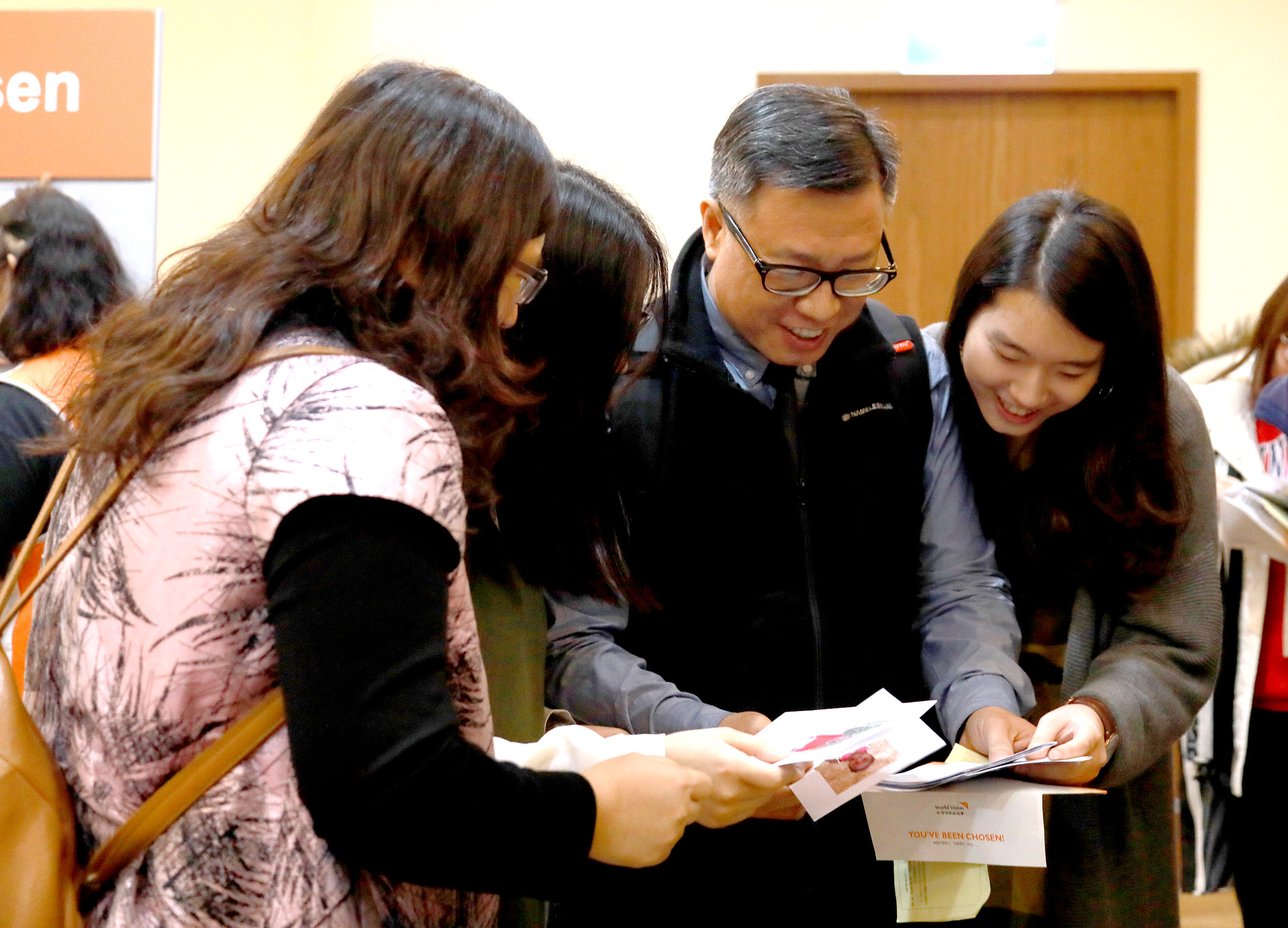 建築師鄧毅仁(右二)全家人一起讀著資助童米莉安來自非洲尚比亞的信件。