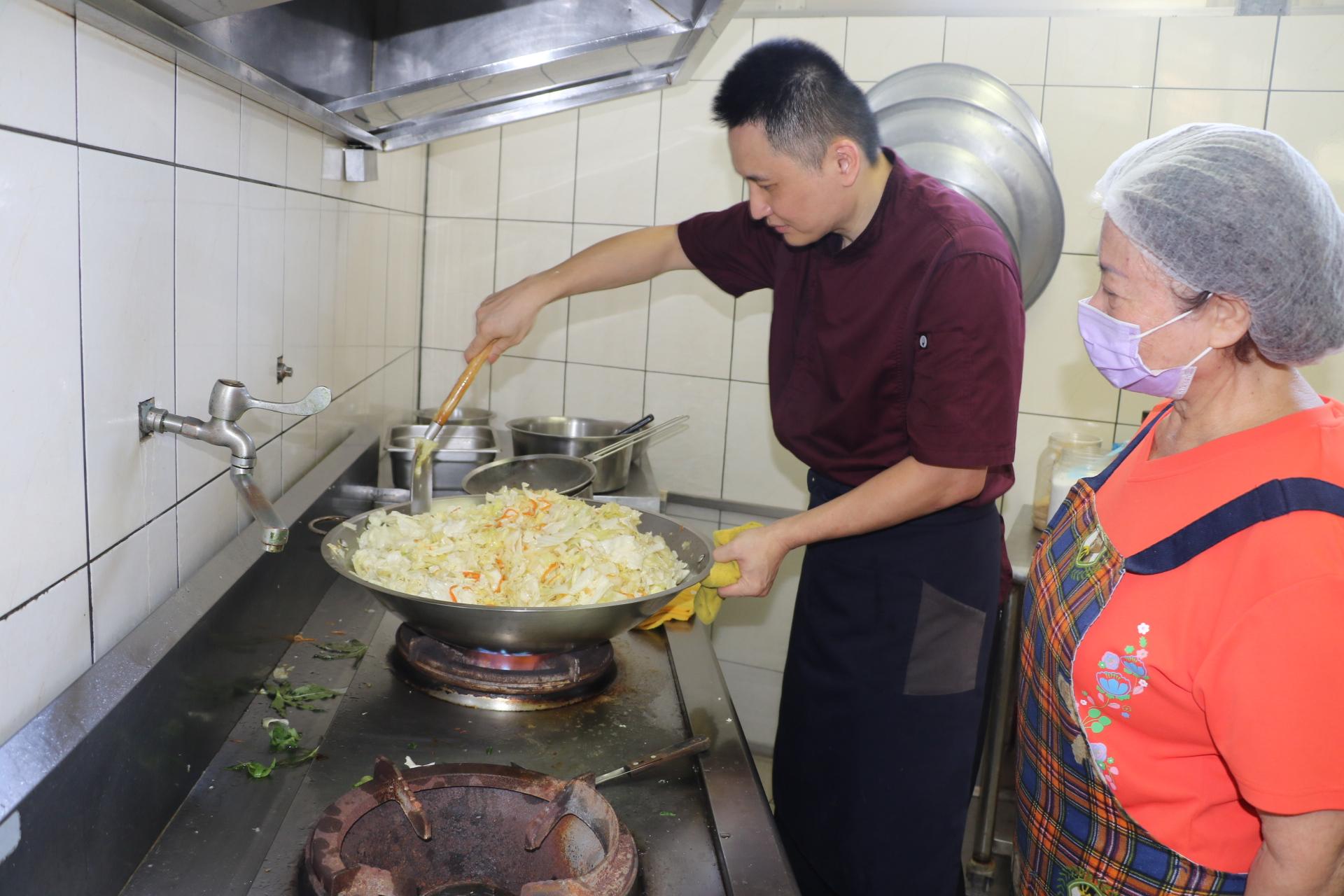 五星級飯店主廚的陳佳瑋專程到新莊牡丹心社區發展協會照顧關懷據點為長輩義煮++志工在一旁討教