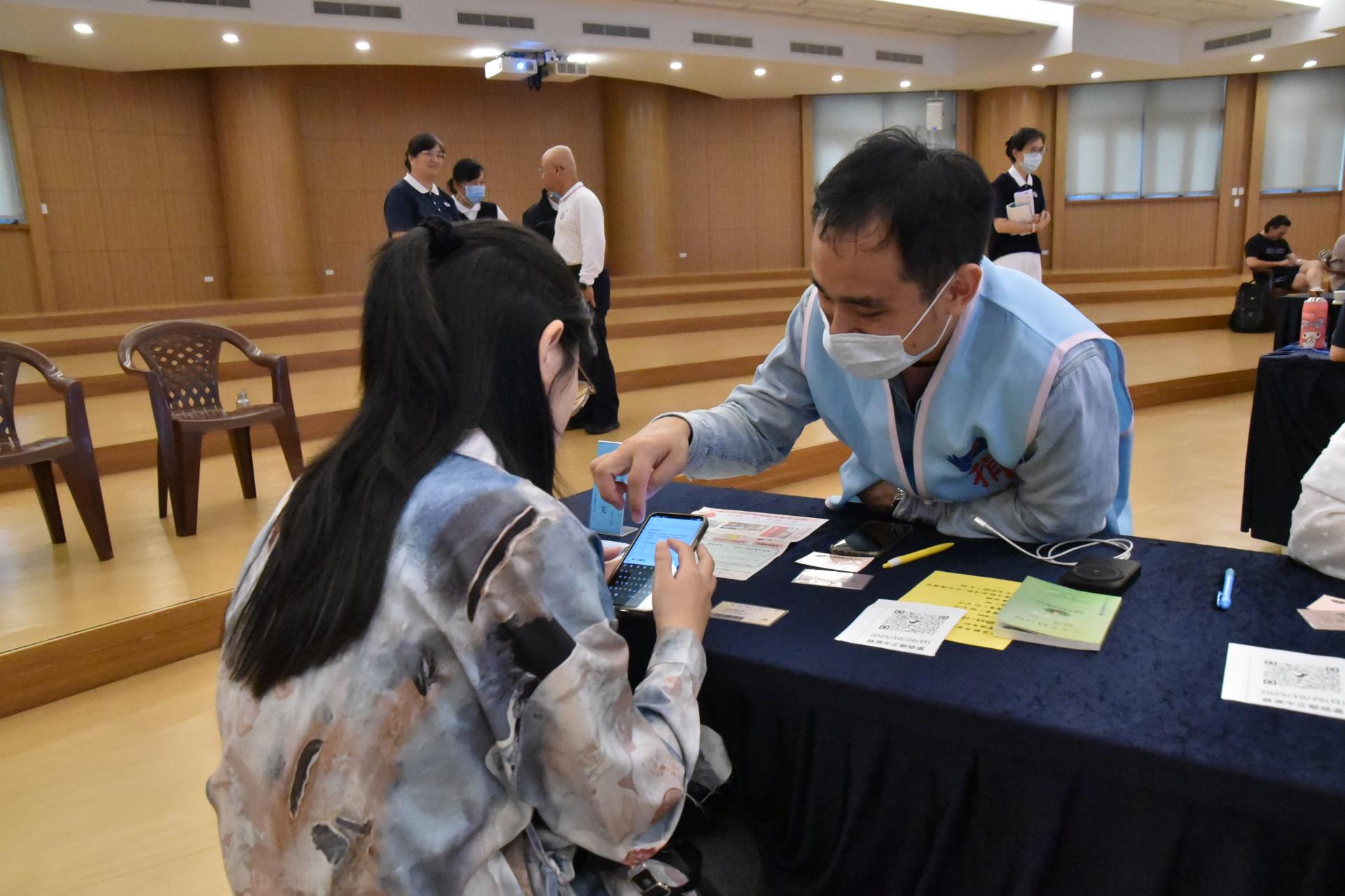 捐贈者李後寬(右)今天在建檔區服務,因為使用手機填表建檔,需要年輕人服務,同時也將自己捐贈的經驗分享給來抽血建檔的會眾,可以安撫他們怕抽血的心情。