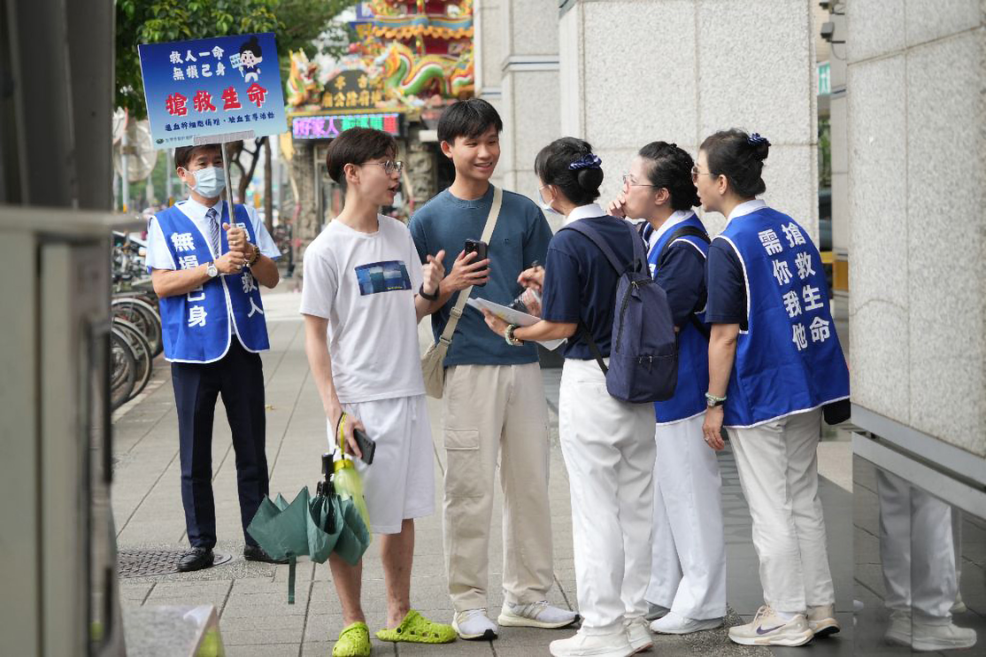 志工在捷運站，耐心向路人解說，希望能邀請更多年輕人挽起袖子，參加造血幹細胞捐贈驗血建檔，幫助血癌患者尋找配對機會。