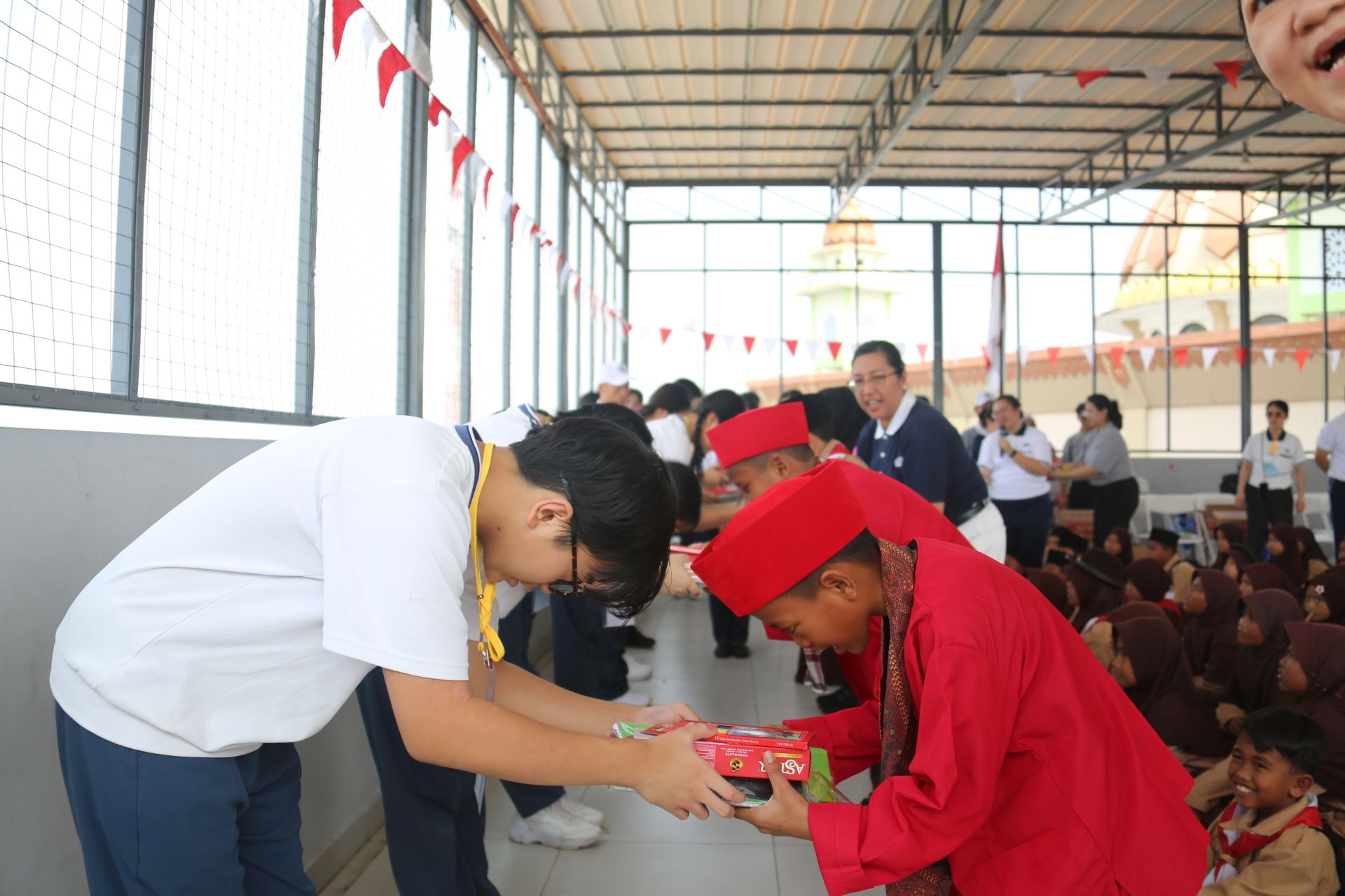 慈中學生在卡馬爾．穆阿拉村旁的努魯伊斯蘭小學，恭敬地將文具與生活用品送給孩子。