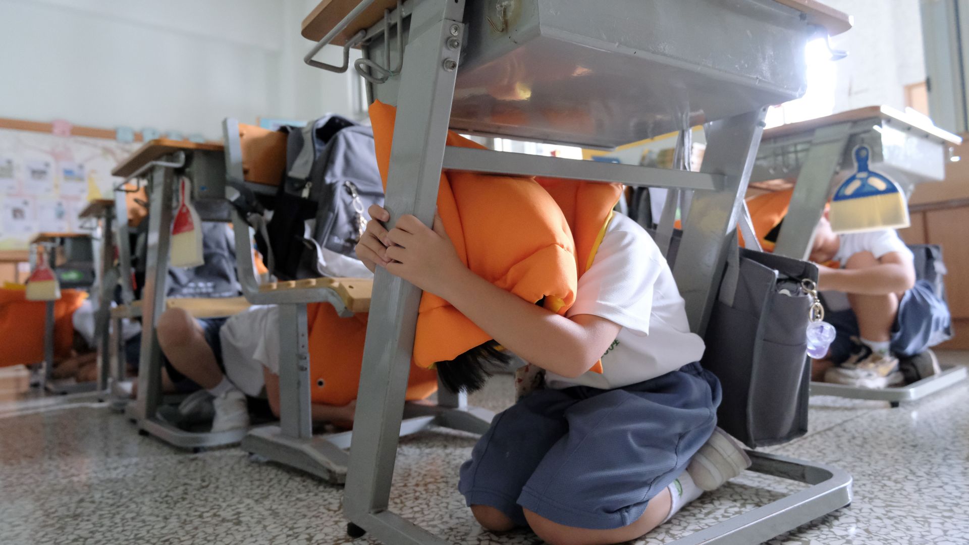 警報聲響，學生迅速的「趴、掩、穩」，進行地震避難動作。