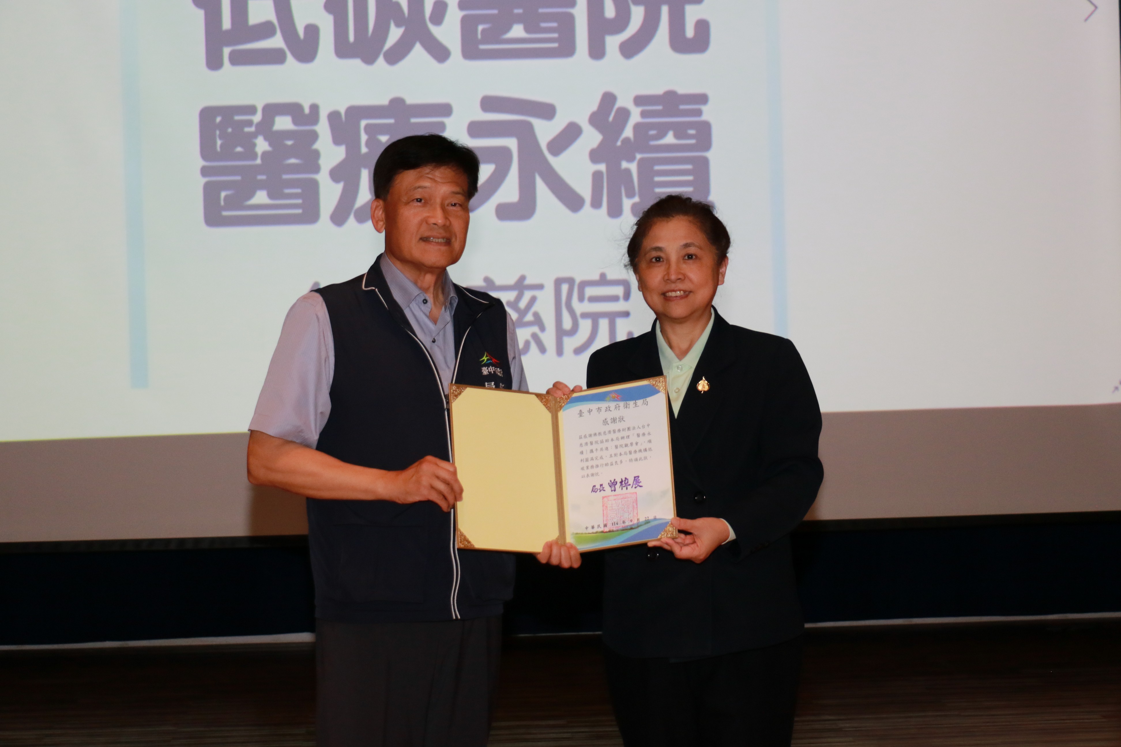 台中市衛生局局長曾梓展(左)頒發感謝狀，由莊淑婷副院長(右)代表台中慈濟醫院接受。