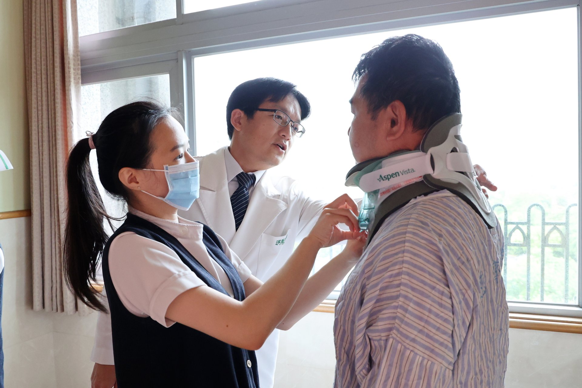 洪祥益主任(中)與個管師林懿璇(左)檢查黃先生(右)的傷口狀況及護頸。