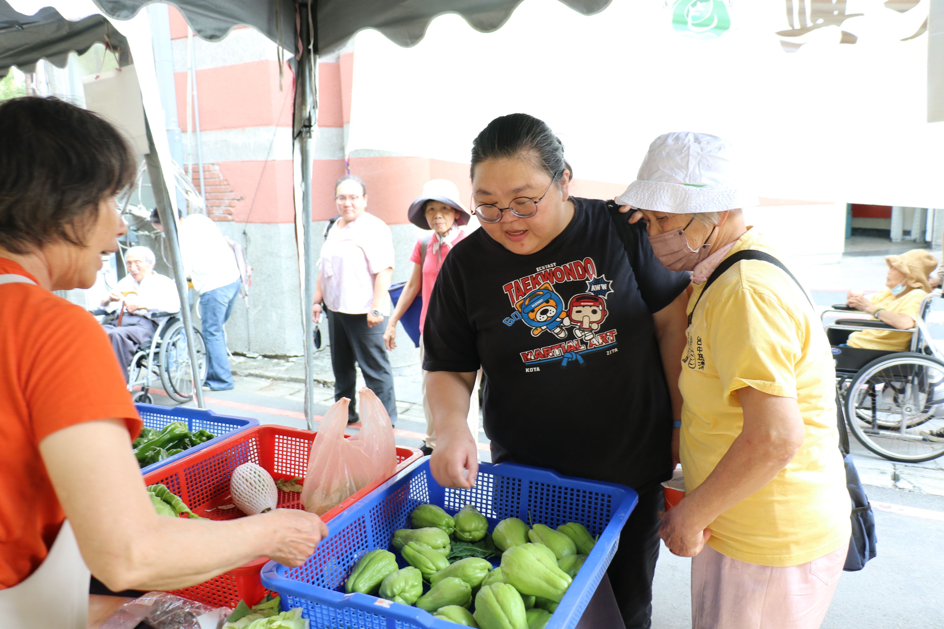 攤位老闆介紹農產品讓長輩連結買菜的經驗，自然地互動對話。