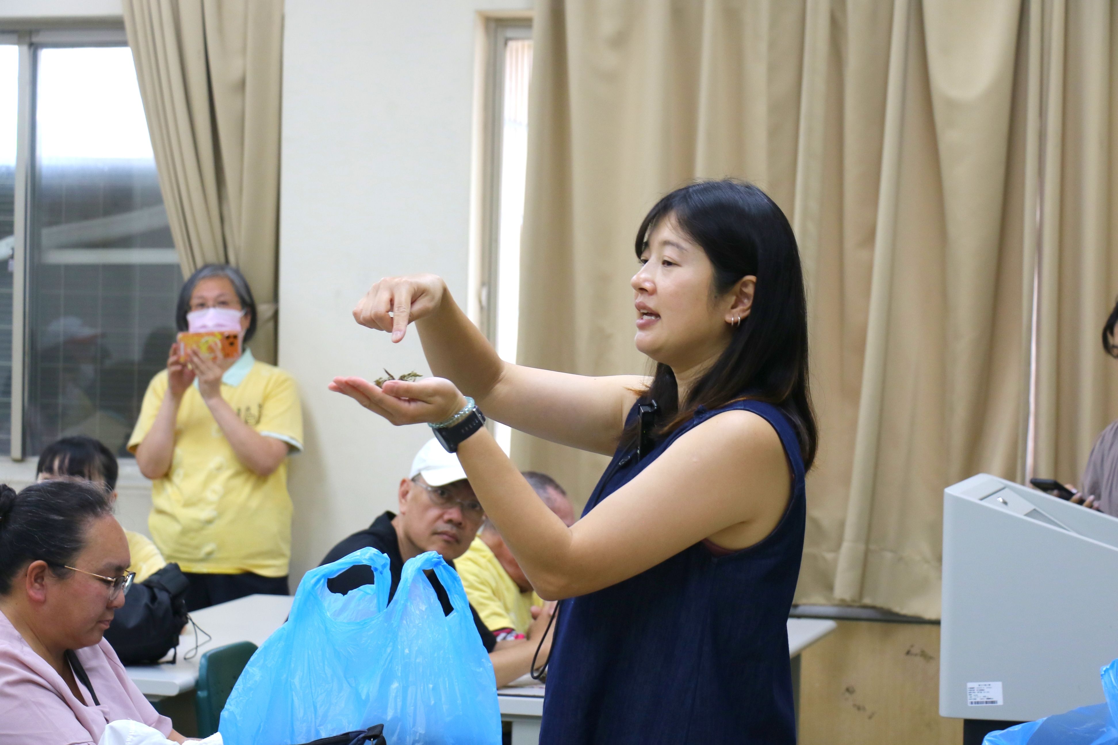 陳千鈴示範把艾草搓揉成絨毛形狀，代替棉花填充香草槌。