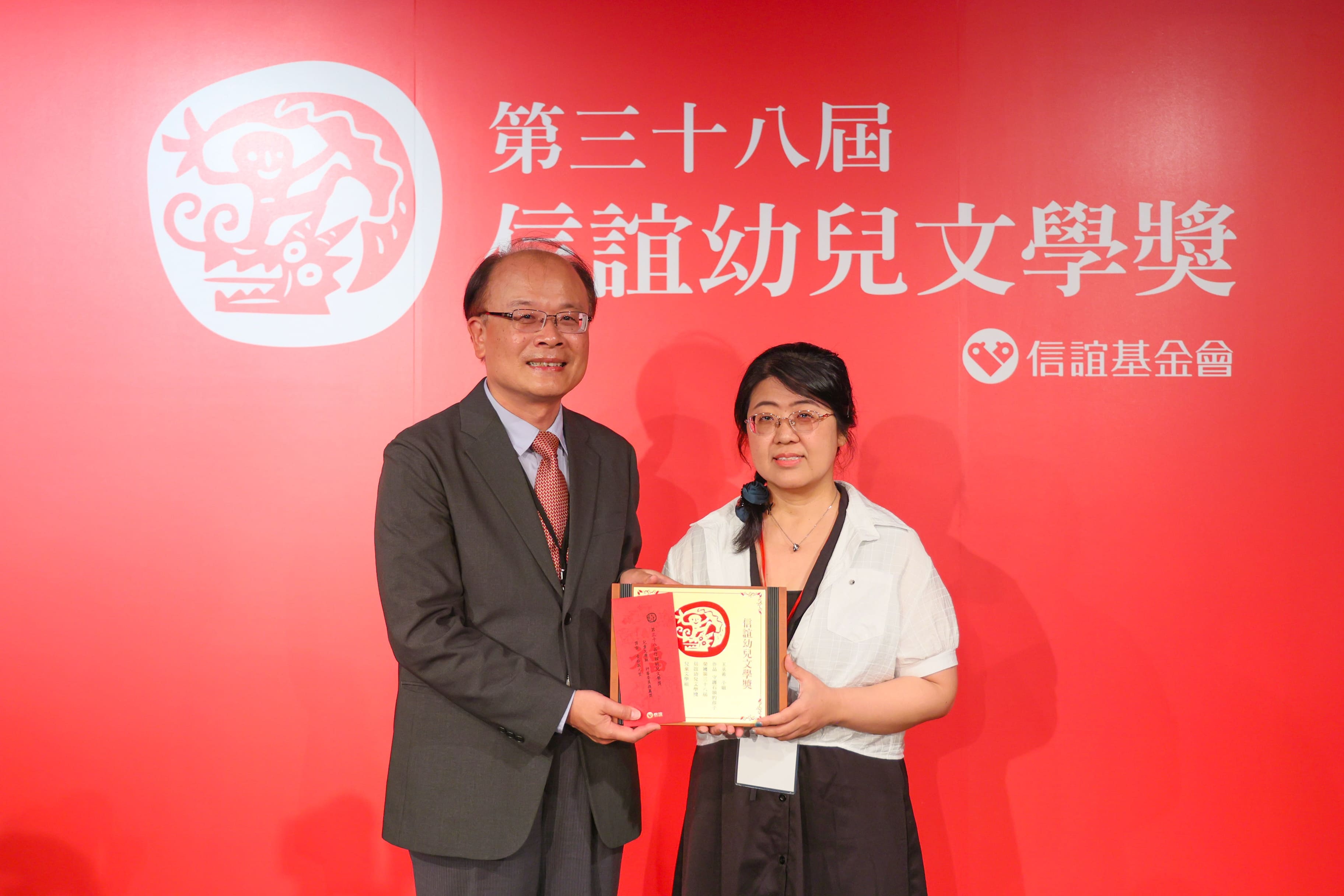 教育部終身教育司梁學政(左)司長頒發兒童文學評審委員推薦獎予文化資產工作者王丞希(右)。