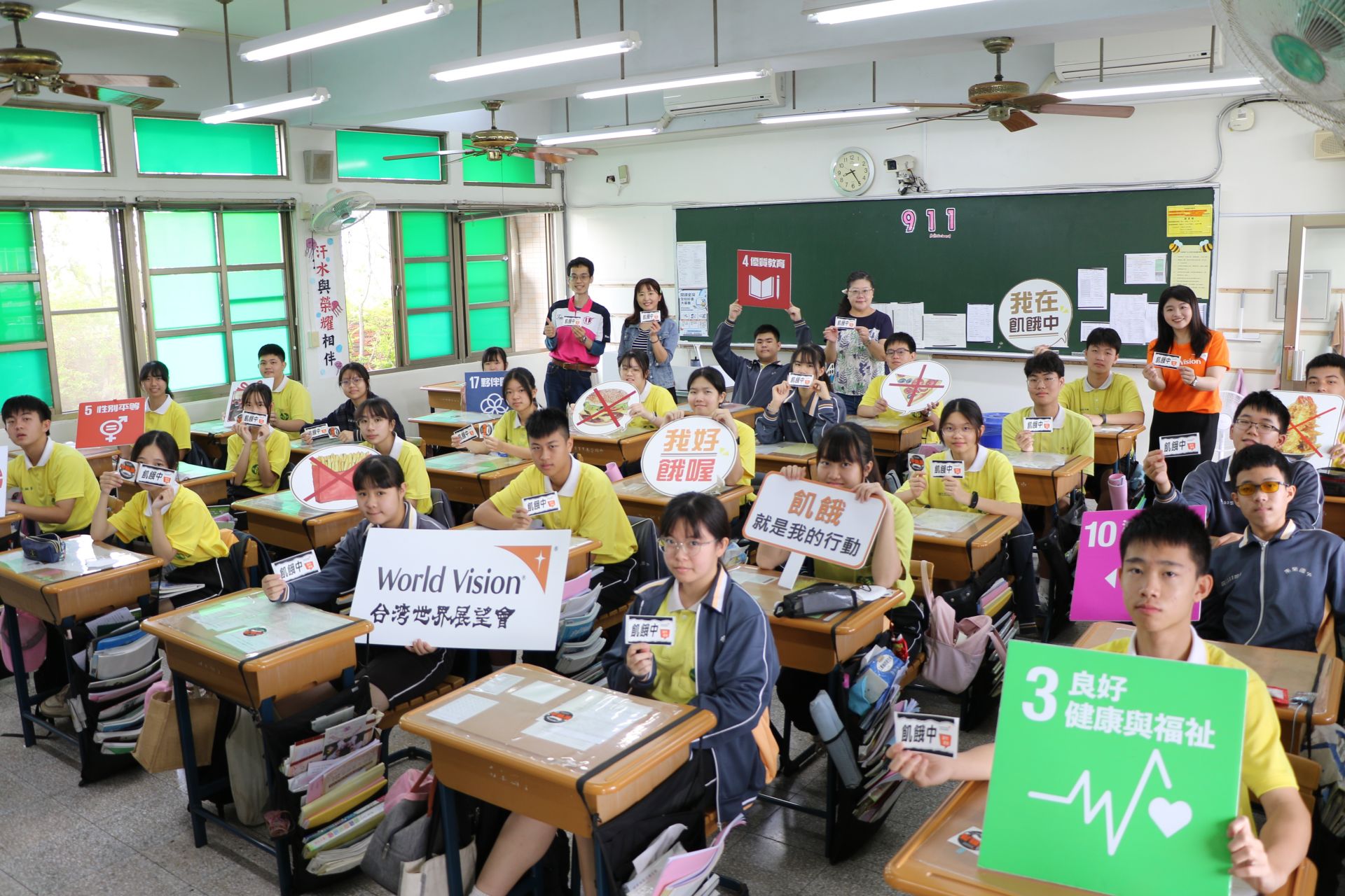 班級學生手持飢餓貼紙與體驗包共同參與飢餓三十活動，以集體行動回應世界地球日主題，展現團隊參與的行動力量。