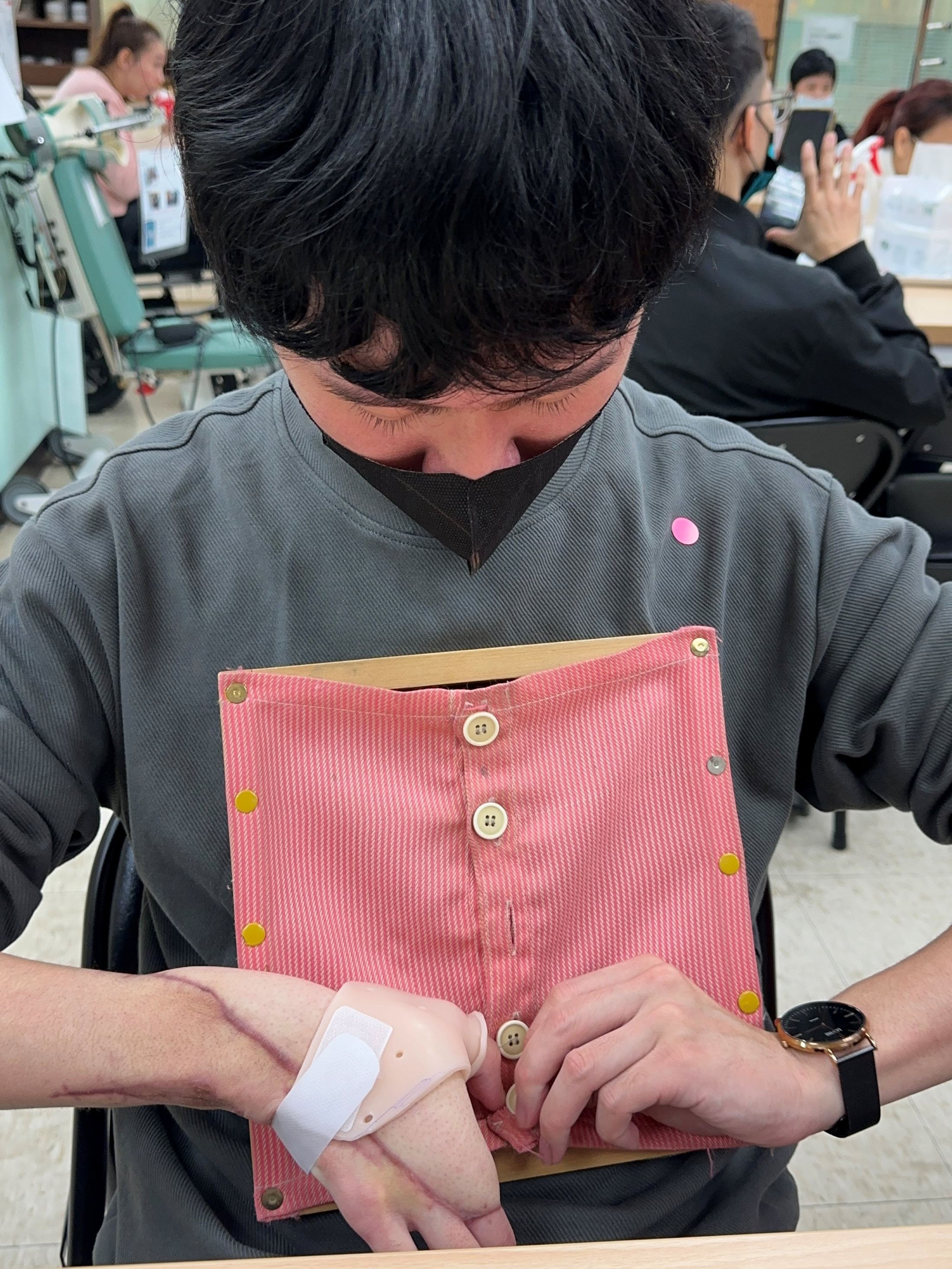 小均在陽光努力復健，復健練習扣衣服扣子等生活自理能力。